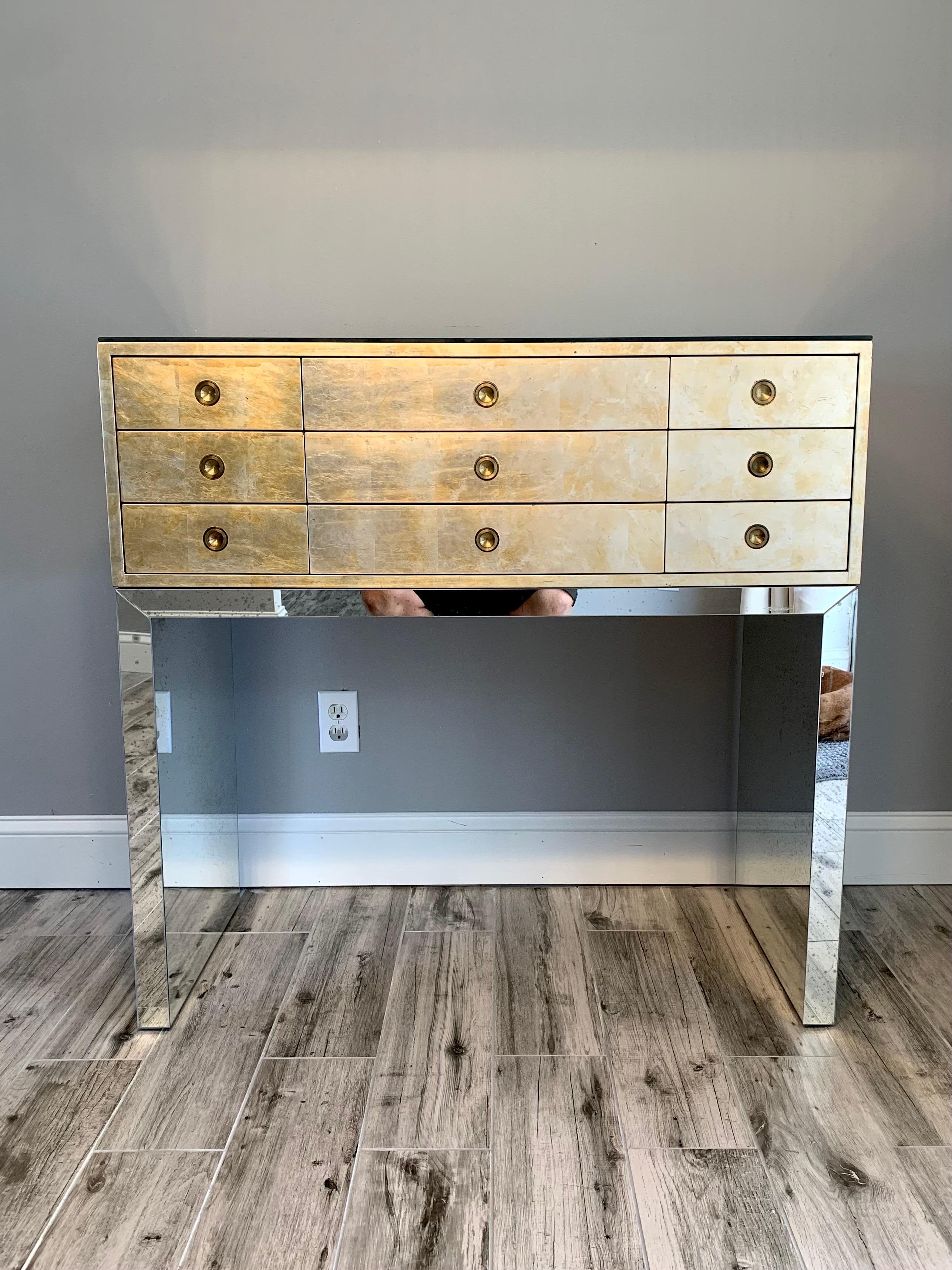 Elegant chest of drawers by Kittinger of Buffalo. Could be used as a console table, mini dresser, or jewelry chest. The cabinet is covered in metal leaf that has gold and silver elements and colors. It appears to be faded gold leaf. 9 total drawers