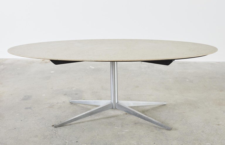 Iconic Mid-Century Modern oval dining table featuring a molded stone top attributed to Florence Knoll. The stone top has beautiful veining and detail with a smooth, beveled bottom edge. Supported by a steel pedestal base measuring 46 inches wide by