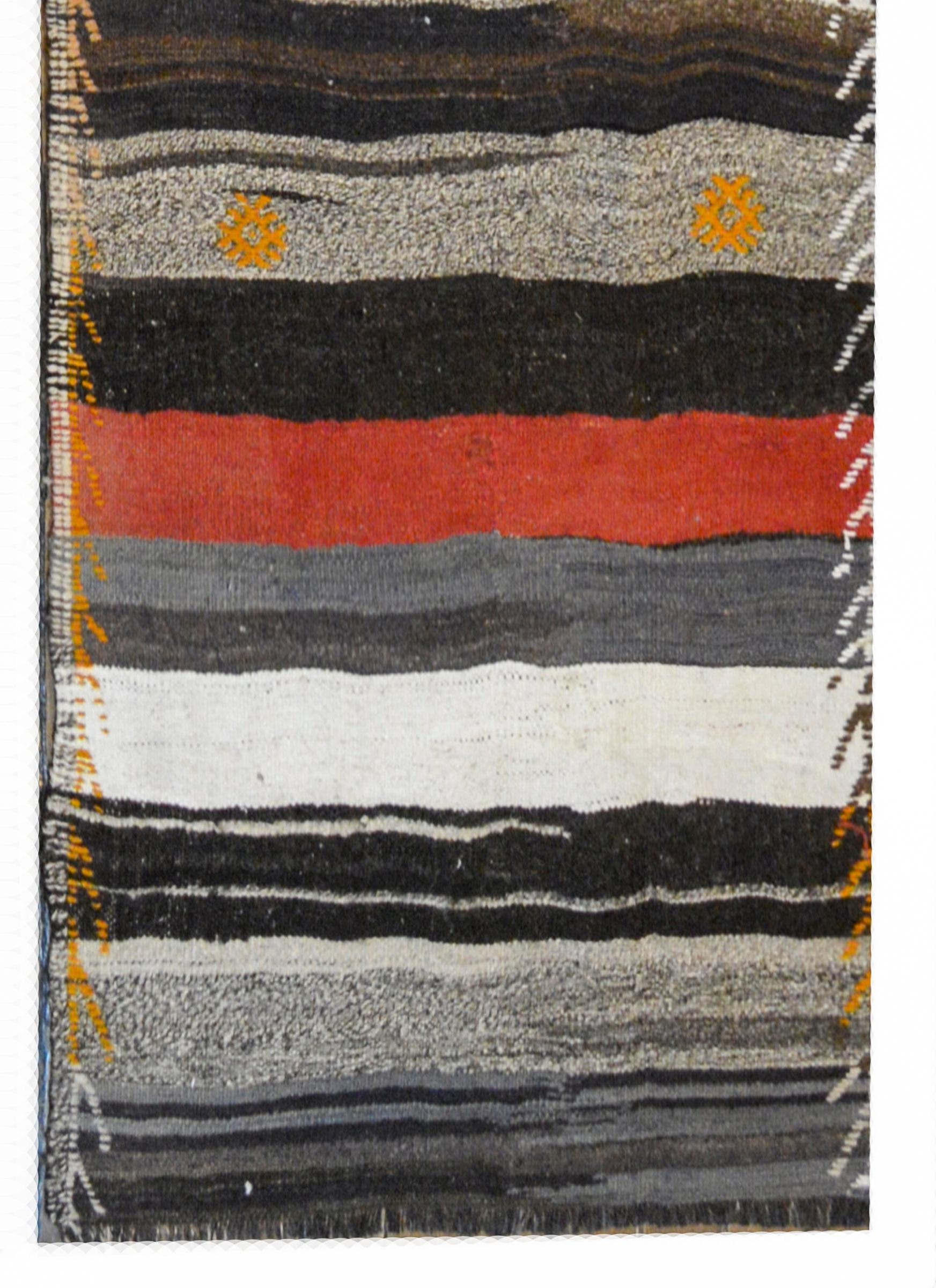 A fantastic mid-20th century Turkish Konya Kilim runner with alternating crimson, orange, black, white, and gray stripes with embroidered stylized flowers and an embroidered border.