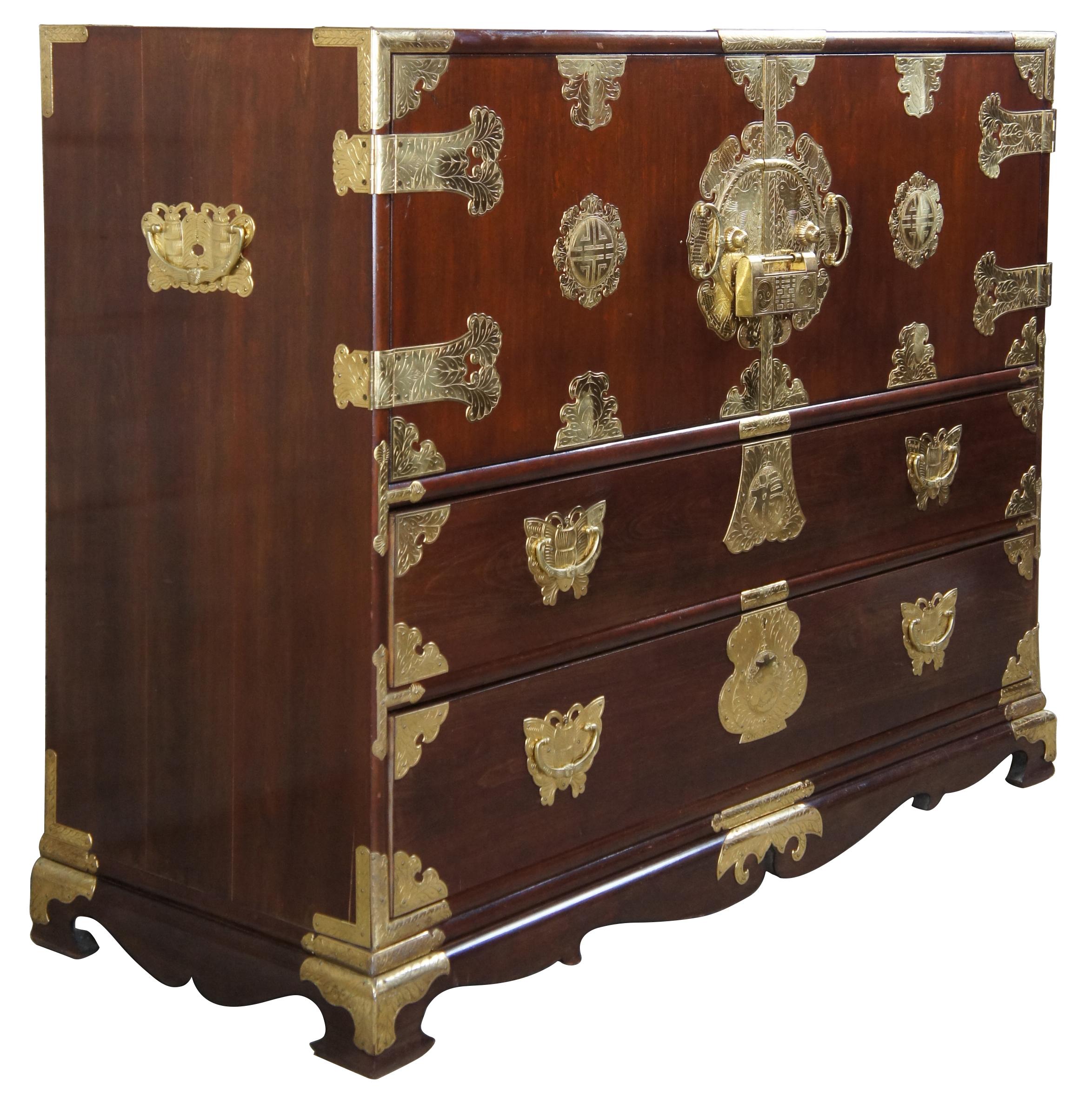 Midcentury Korean brass mounted elm sideboard / tansu, with profuse engraved brass butterfly and medallion mounts, two blind doors revealing five fitted interior upper drawers, and two lower long drawers. Includes ornate brass lock and key and