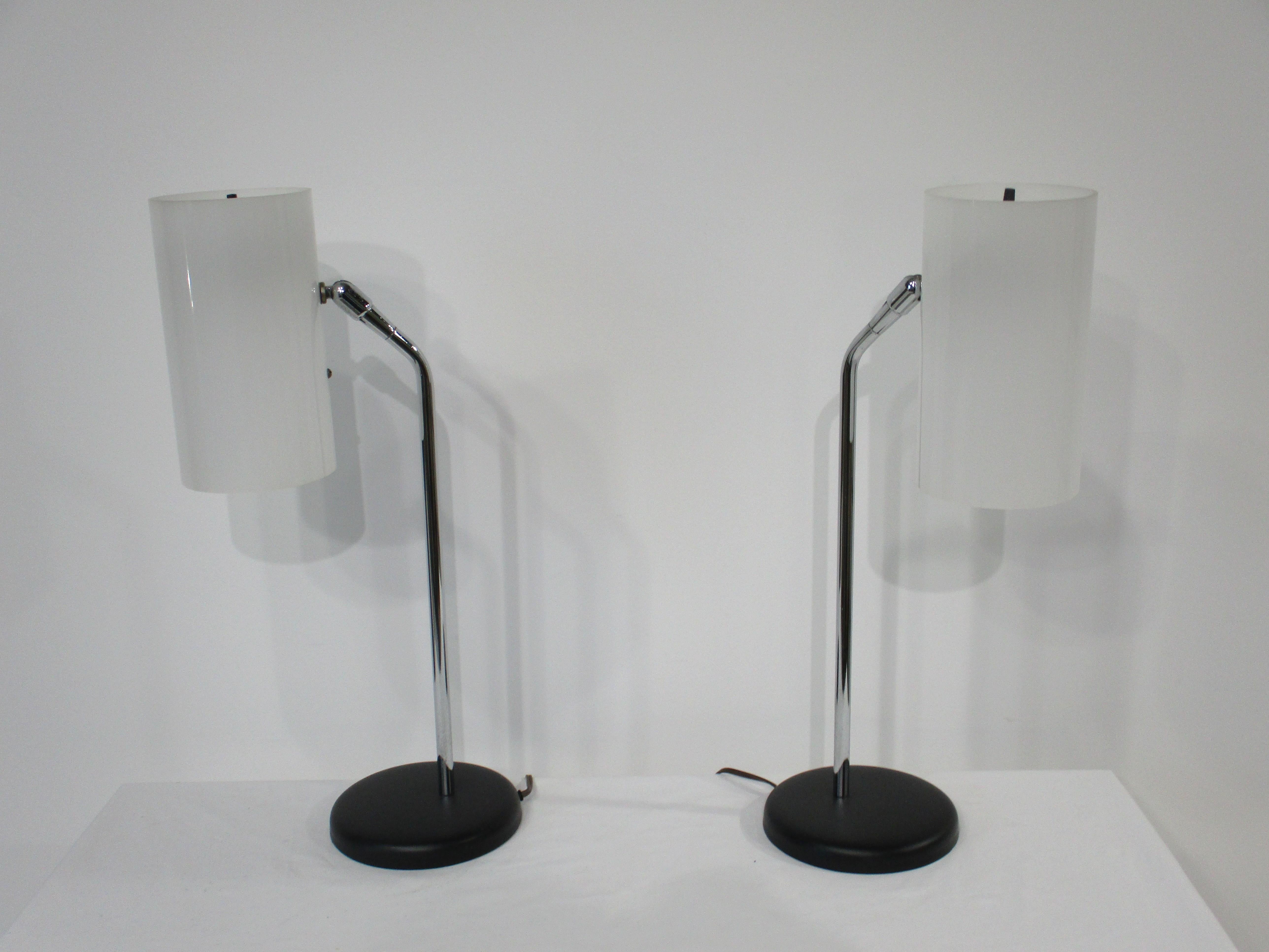 Ein Paar elegante Tisch- oder Nachttischlampen aus der Mitte des Jahrhunderts mit undurchsichtigen zylindrischen Lucite-Schirmen. An der Oberseite jeder Leuchte befindet sich ein Drehschalter mit drehbaren Schirmen, die auf verchromten Stielen und