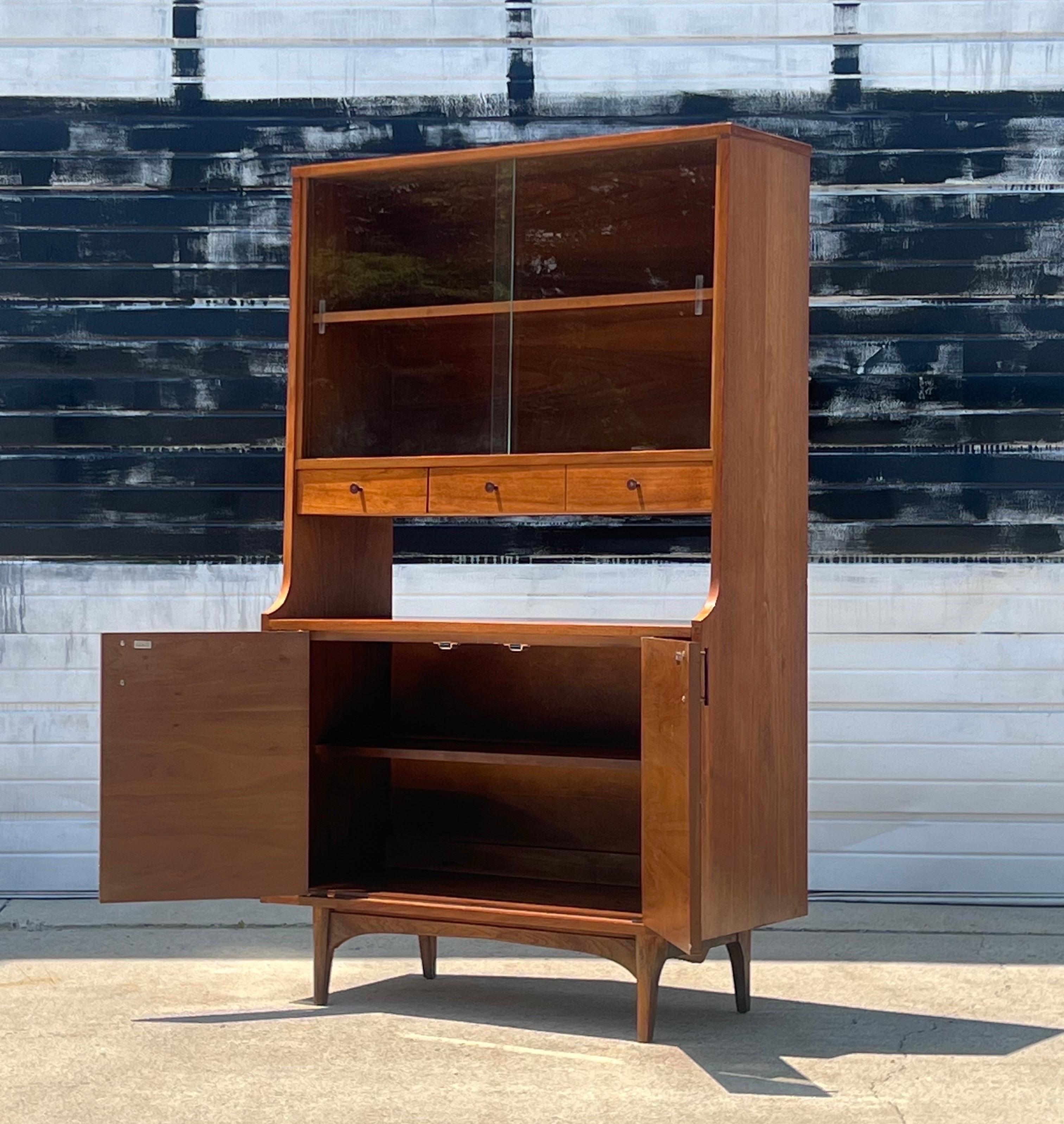 Gorgeous mid-century walnut China cabinet or bar cabinet by Kroehler. Beautiful rosewood accents on the drawer pulls and inlays. A great item for multiple purposes. Bookshelf, media, barware, dining, etc. Lots of storage options below, center or
