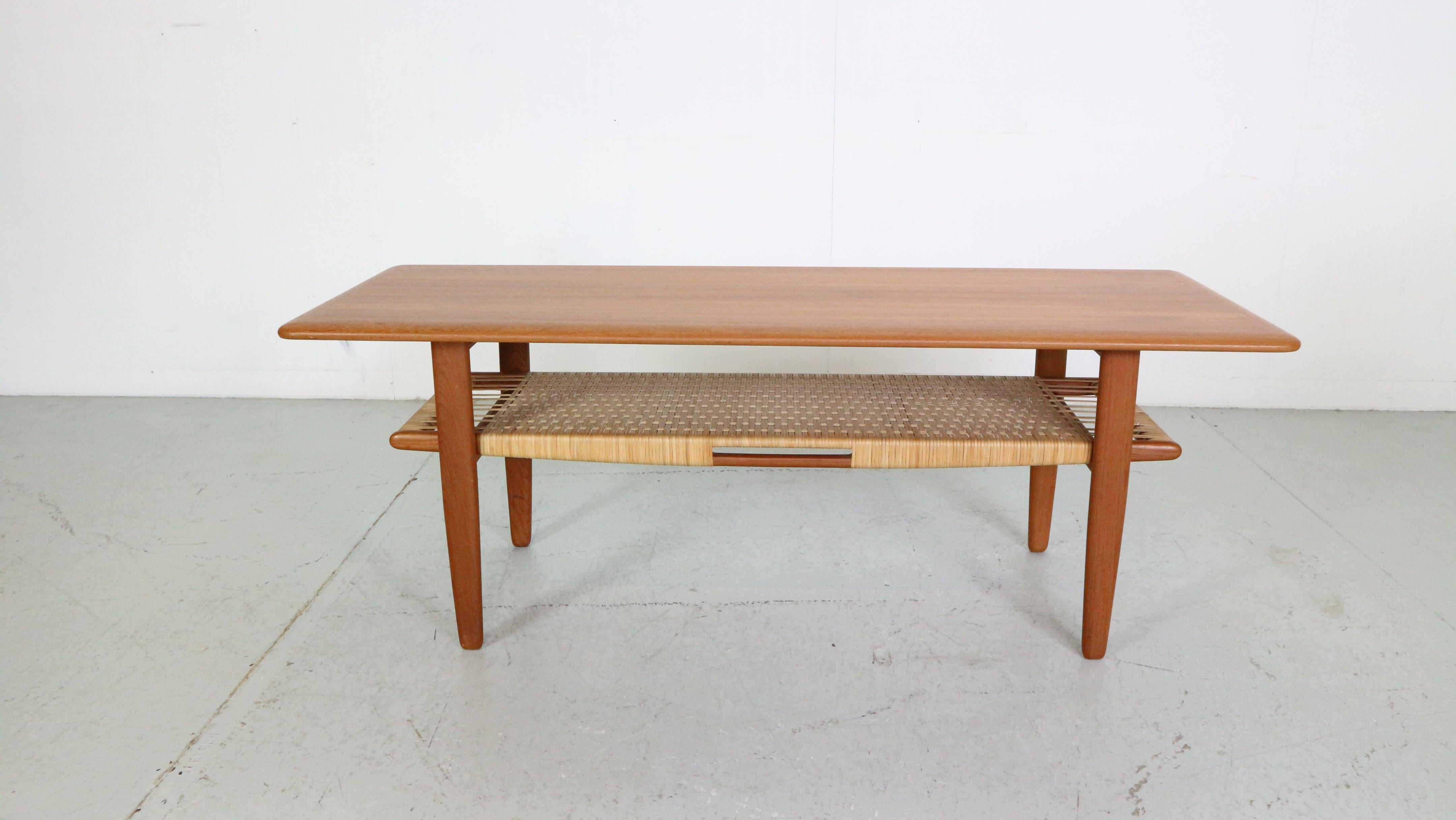 Mid- Century modern period coffee table designed by famous Danish furniture designer Kurt Østervig and manufactured by Jason Møbler in Denmark in the 1950s. 

The table features beautiful rounded table top corners and a ratan storage shelf for