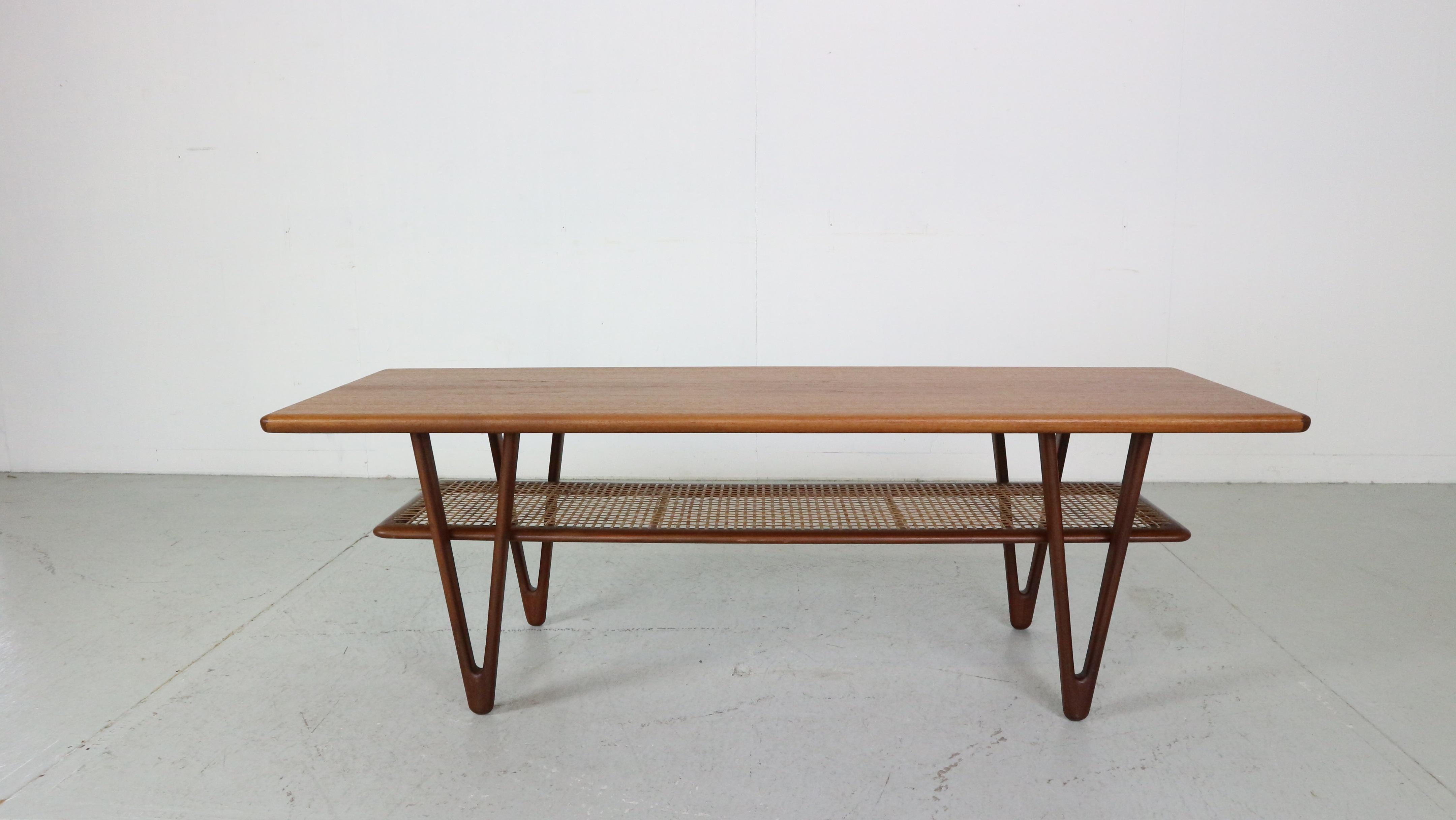 Mid- Century modern period coffee table designed by famous Danish furniture designer Kurt Østervig, Denmark in the 1950s. 

This stunning sculpted coffee table features unique triangular legs with second tier cane shelf. Raised edge teak top