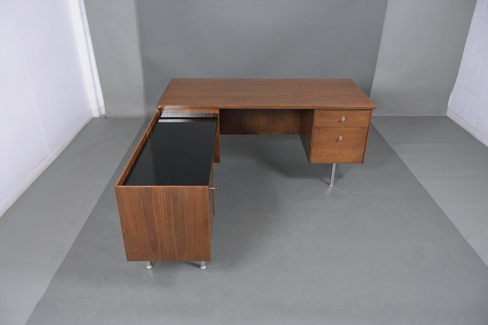 An extraordinary Mid-Century Modern 1960s desk crafted out of walnut wood professionally restored and finished by our craftsmen in the house. This piece has been newly stained in a walnut color with a lacquered finish and features an L-shape design.