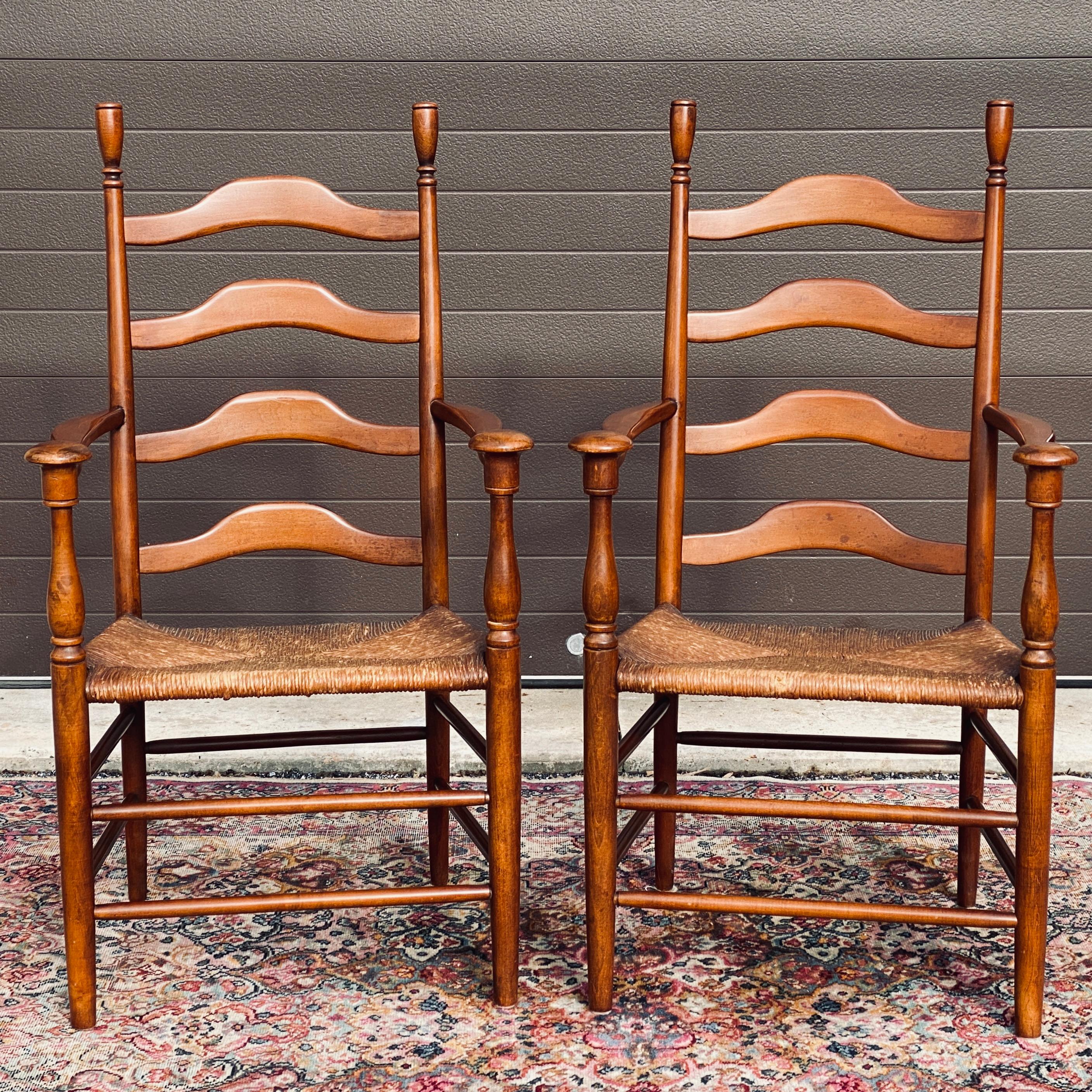 Unusual pair of ladderback armchairs with rush seats, mushroom cap arms, and solid hardwood frames possibly birch. Circa mid 20th century unmarked possibly earlier. 