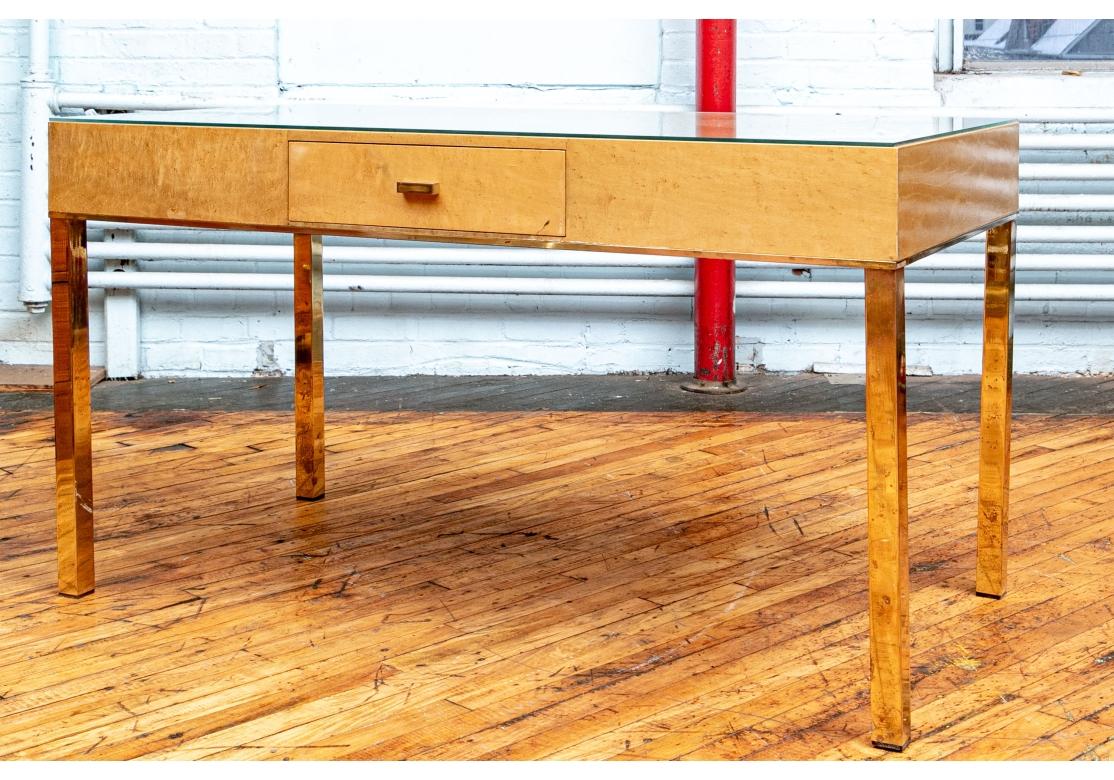 Un'elegante scrivania di metà secolo dalla forma semplice e raffinata. Con un unico cassetto a grembiule con un tiretto rettangolare in ottone. La cassa è dotata di una fascia inferiore in ottone e poggia su gambe quadrate in ottone. Dotato di un