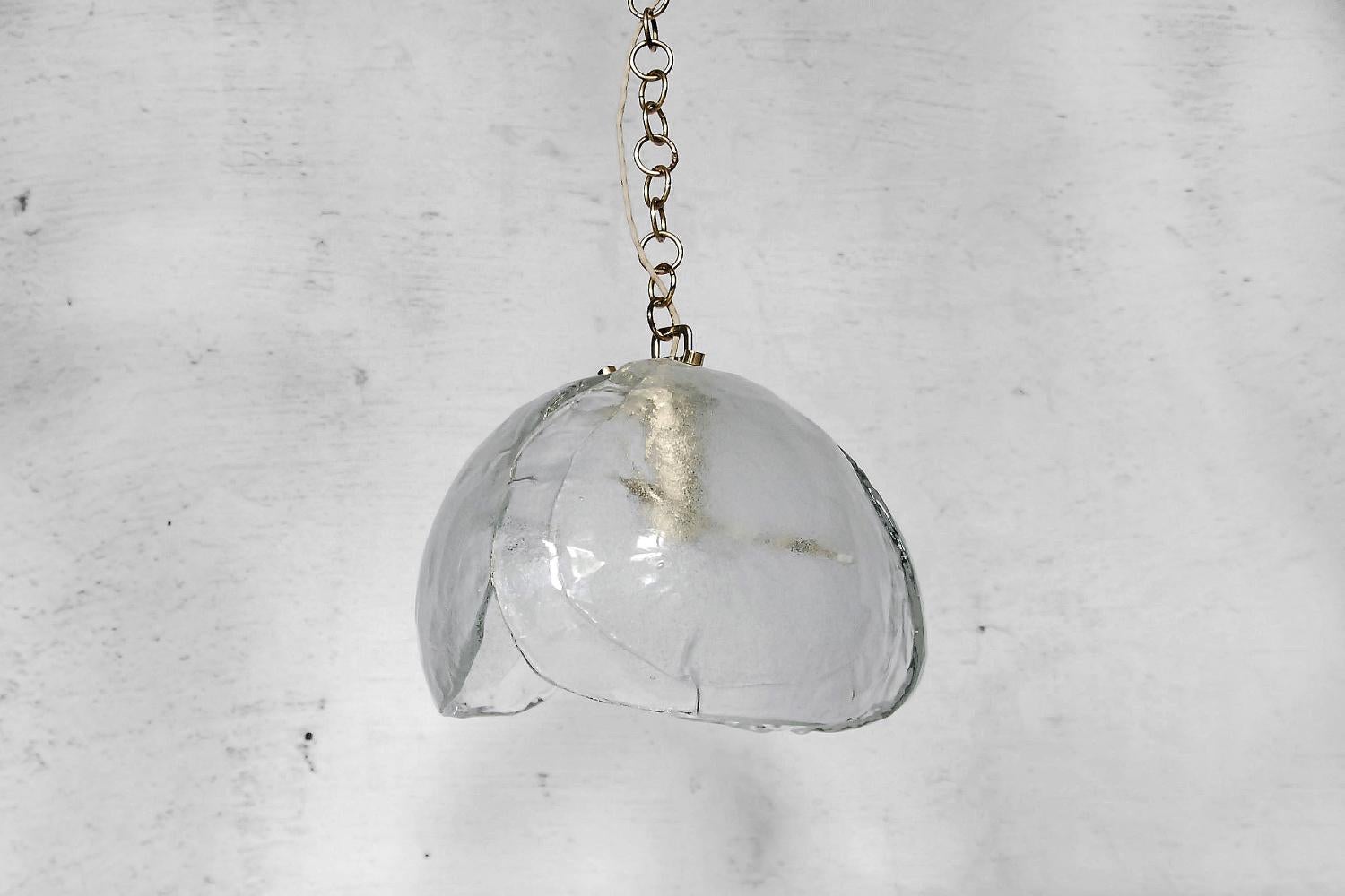 This pendant lamp was manufactured by Kaiser Leuchten during the 1960s. The shade is made from Italian Mazzega Glass from Murano. Its shape resembles the blooming flower. The shell and chain is made from brass. The lamp is large and heavy.