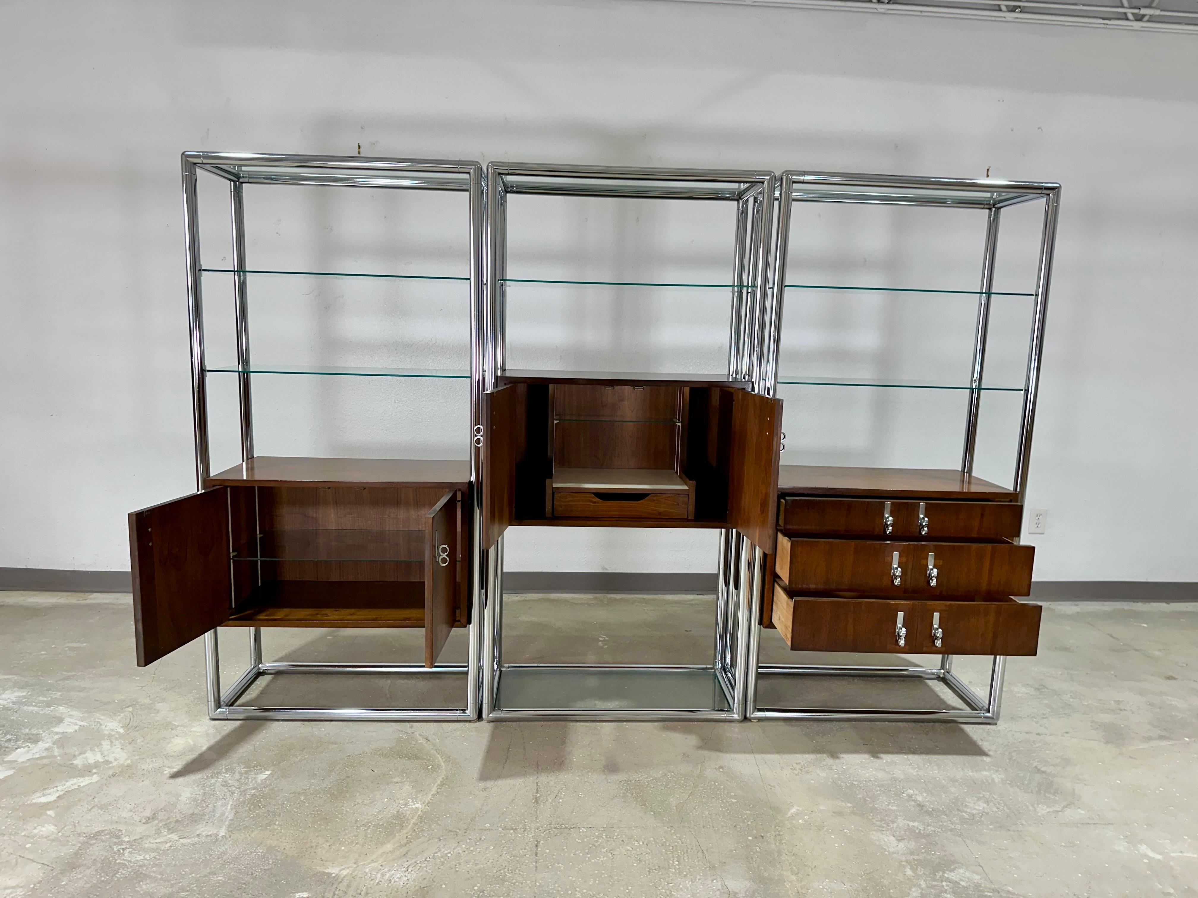 Mid Century Modern 3 Bay Free Standing Lane Walnut, Chrome and Glass Wall Unit/Room Divider c.1970’s. Etagere bays can be used individually or together as shown. Cases are finished on back. Each bay is 67”H x 33.5”W x 16”D.

Each Etagere is composed