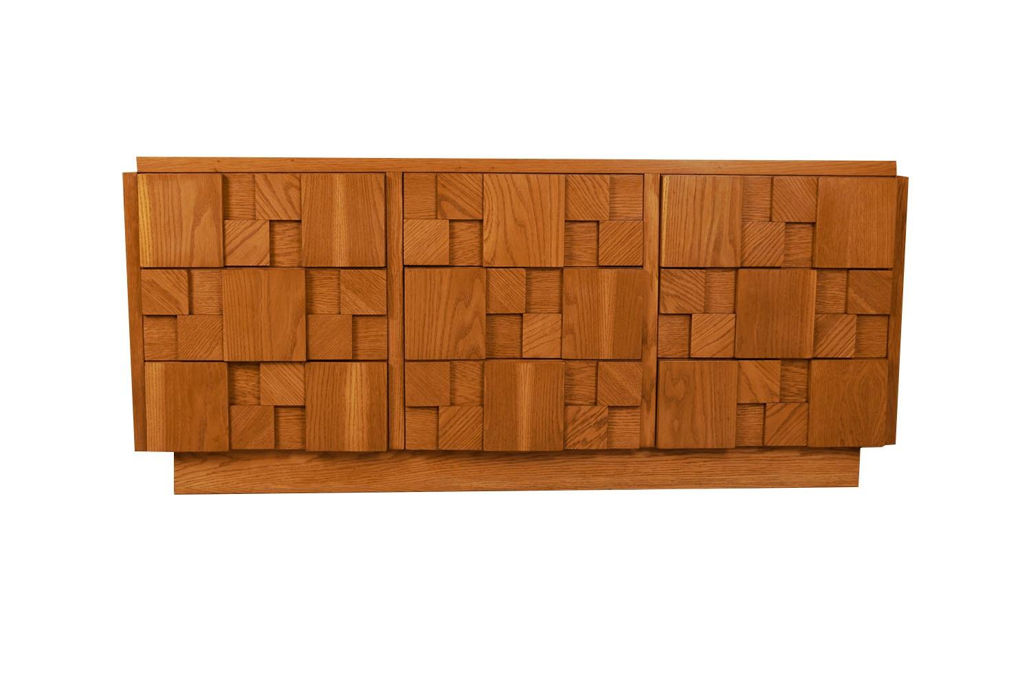 A unique cubist style nine drawer dresser by Lane furniture features the brutalist style made popular by Paul Evans. Bold and impressive, with heavy solid wood construction, figured geometric drawer fronts. The nine-drawer dresser offers plenty of