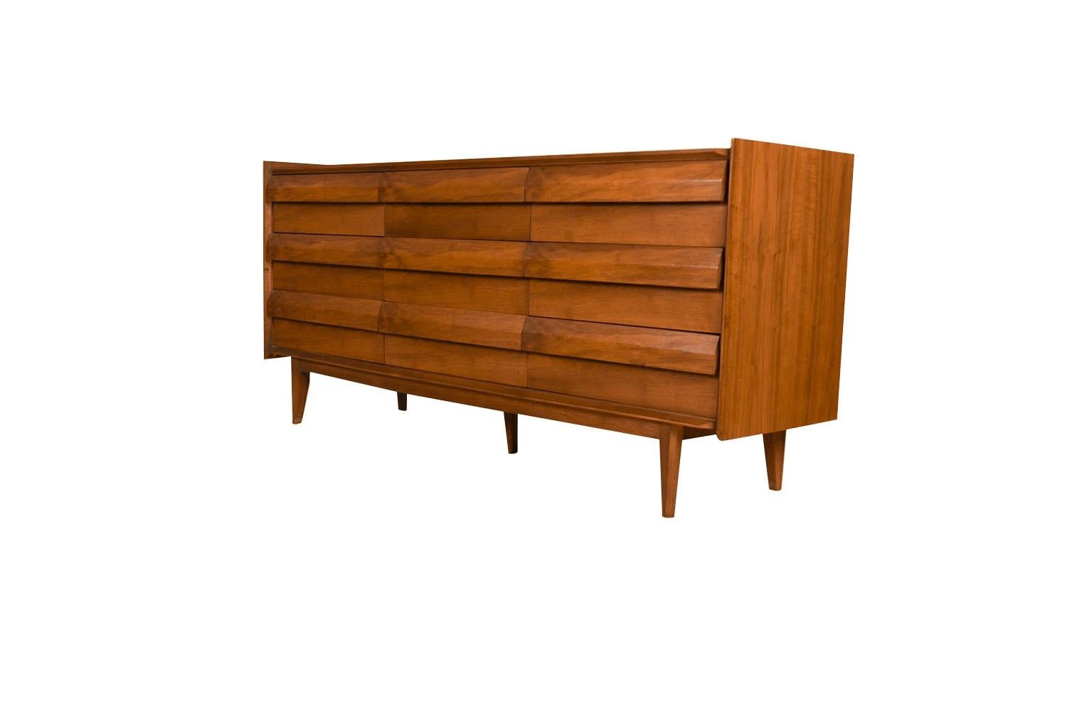 An elegant Mid-Century Modern Lane First Edition 9-Drawer Dresser in Walnut, c. 1960s. This is a beautiful example of Mid-Century craftsmanship by Lane Furniture. Features nine louvered drawers. An extremely well made and solid piece in great