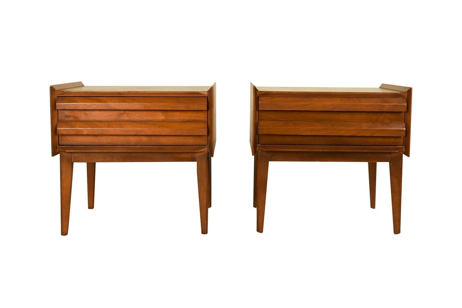 An elegant Mid Century Modern pair of nightstands/end tables designed by Andre Bus for the First Edition Collection by Lane c. 1960s. This is a beautiful example of Mid-Century craftsmanship by Lane Furniture. Each feature one deep drawer, with a