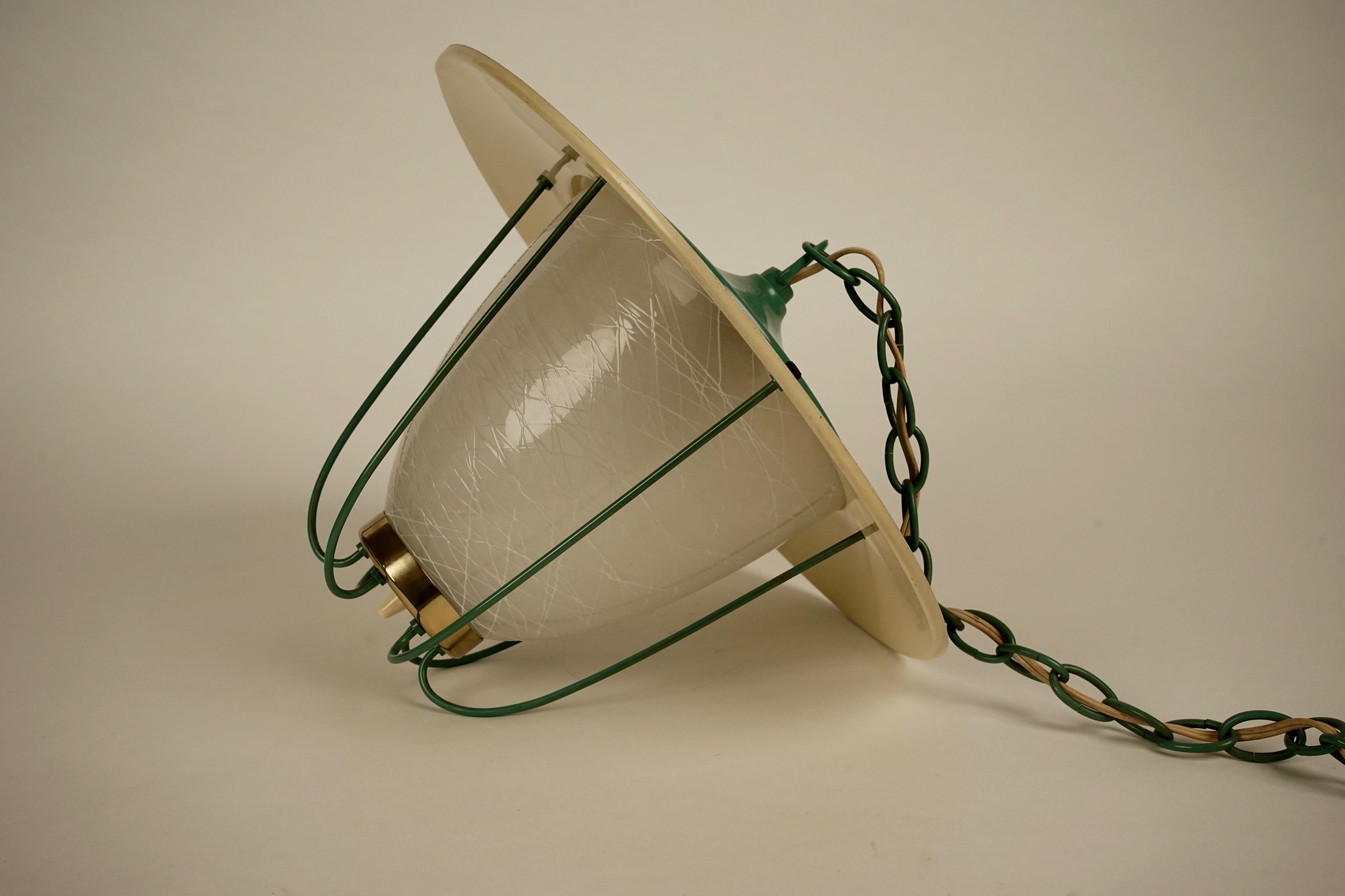 This Tokio lamp from Kalmar is in wonderful condition. The metal top, chain ceiling cup and cage are sprayed linden green, the glass has been frosted with a pattern. The cage is held to the top with elegant metal balls and at the bottom to a brass