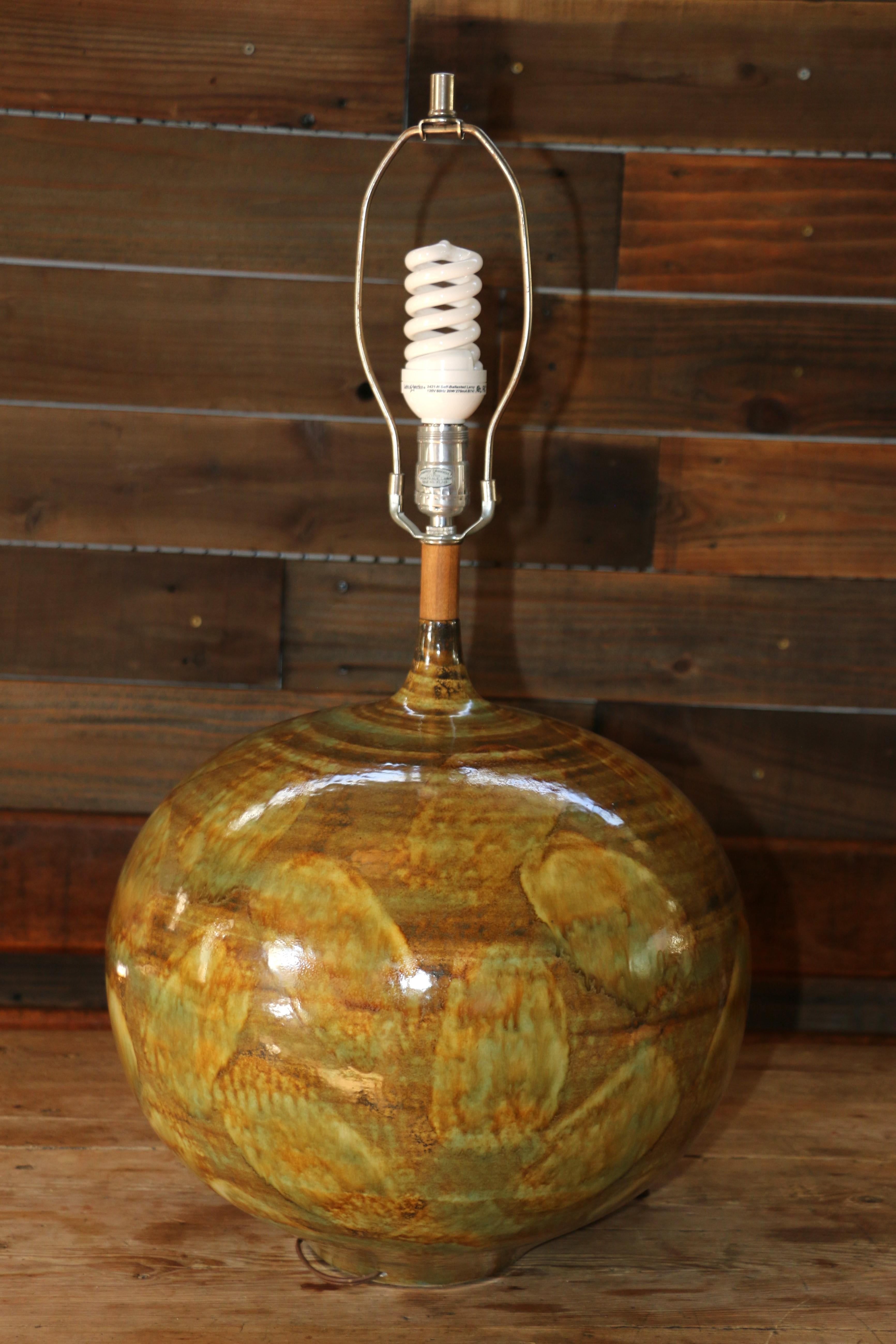 Merveilleuse lampe de table en poterie vintage. Cette lampe de table étonnante présente une glaçure goutte à goutte fascinante dans des tons neutres sophistiqués et des tons dorés opulents. Ornée d'un détail en teck sur le col, cette pièce est un