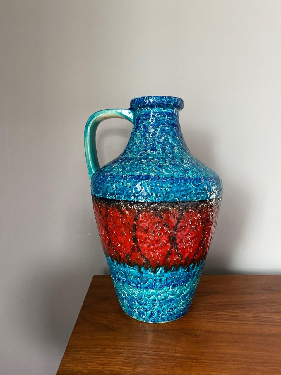 Stunning mid-century large fat lava vase. This beautiful piece is glazed in a deep ocean blue with a red glaze band around it in the middle. The encrusted glaze that typify these pieces glistens with light. Classic Mid-Century pieces.

  