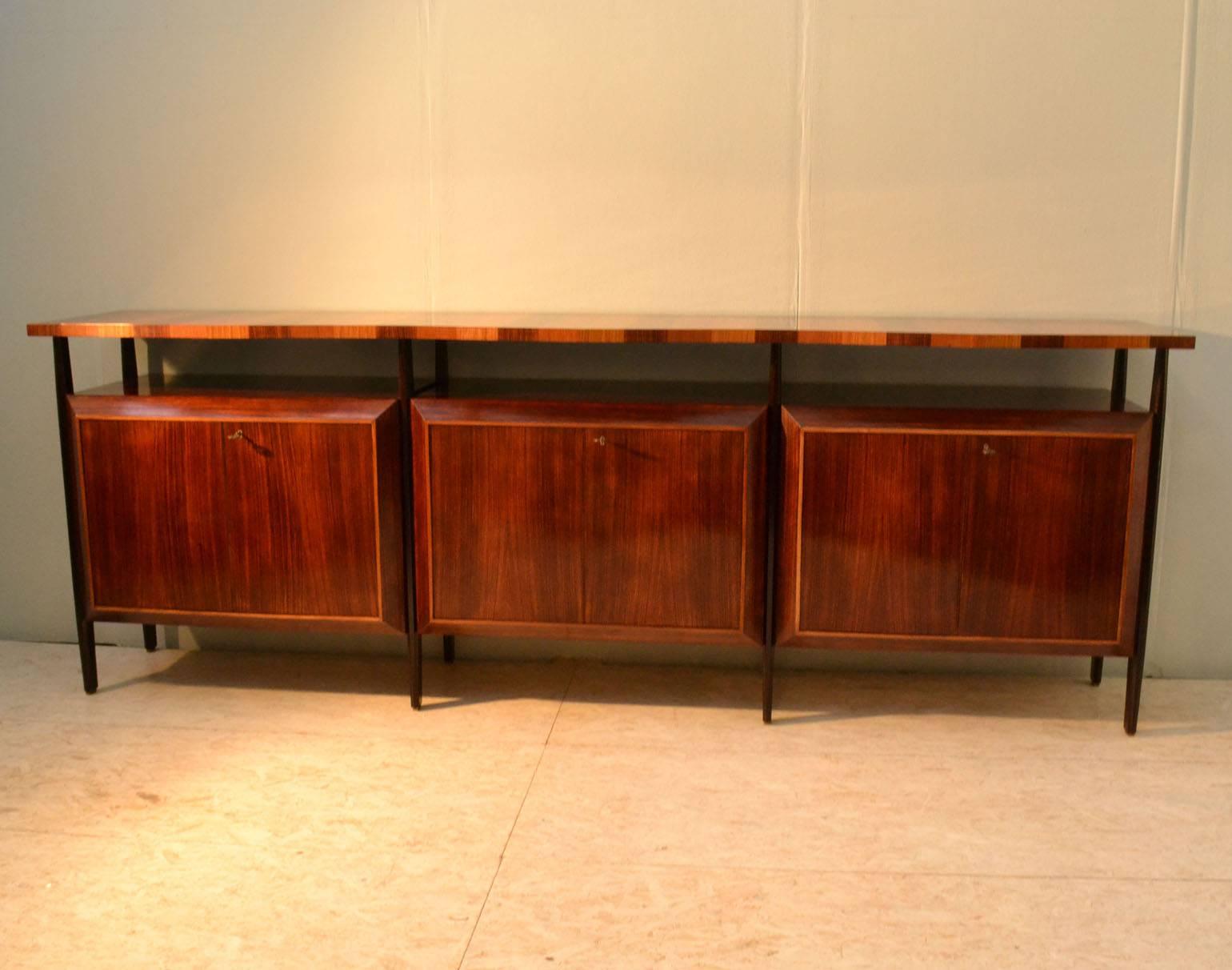 Unusual handcrafted sideboard with three units in palisander veneer with diamond shaped fronts doors, suspended on ebonised legs. An overlapping zig-zag edge top floats on top of the legs in borders of three colored wood; Indian palisander, blond