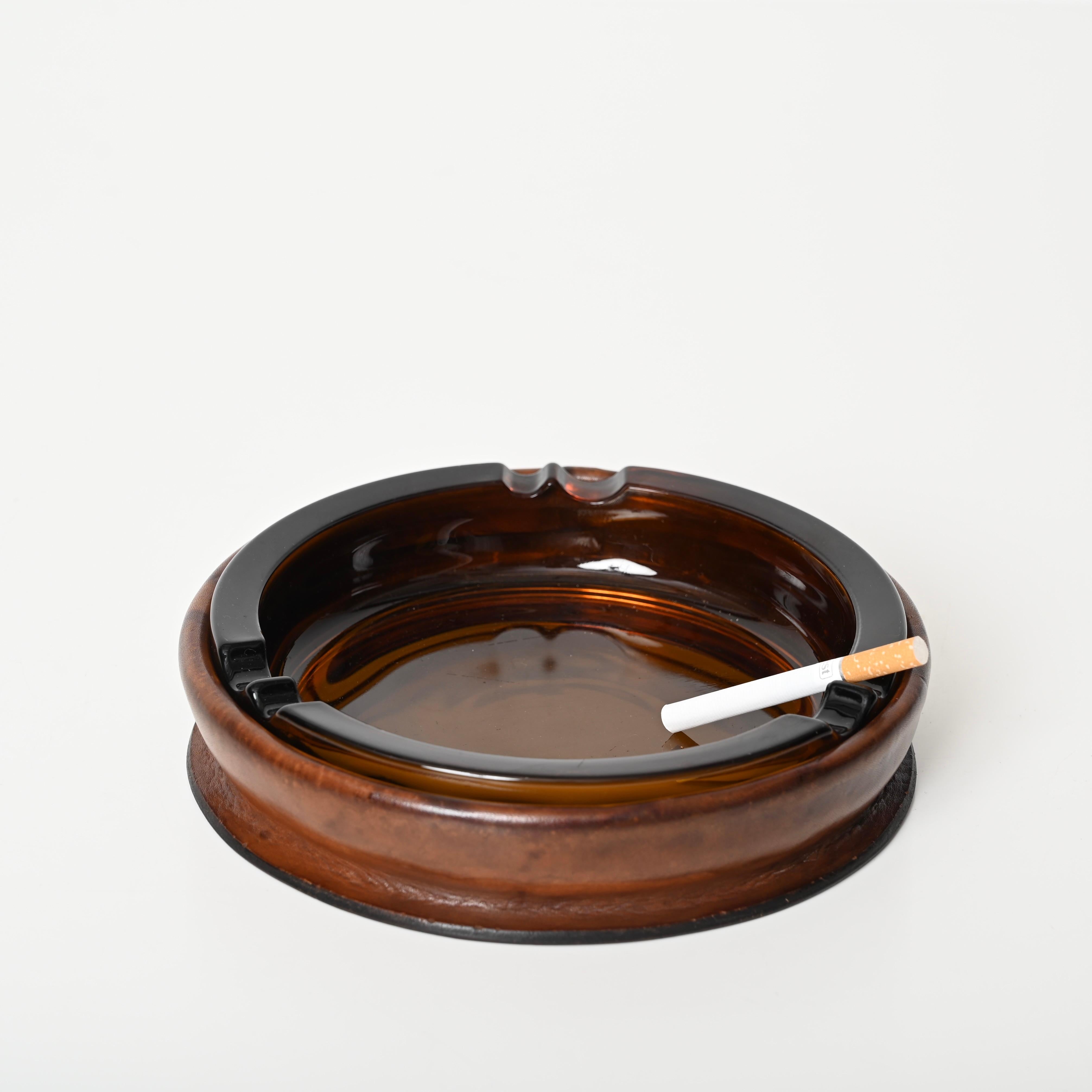Splendido posacenere italiano di grandi dimensioni in pelle marrone piegata e vetro arancione. Questo splendido pezzo è stato prodotto in Italia negli anni '60, seguendo lo stile di Jacques Adnet. 

Questo posacenere incredibilmente elegante è in