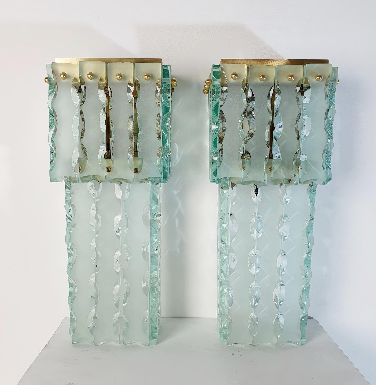 Ein Paar große und schwere Wandleuchter aus Muranoglas, handgefertigt, sowie Strukturen, die speziell für dieses Glas angefertigt wurden. von Mazzega. Jede Leuchte besteht aus großen Stäben aus klarem Glas, die von einer Messingkugel gehalten