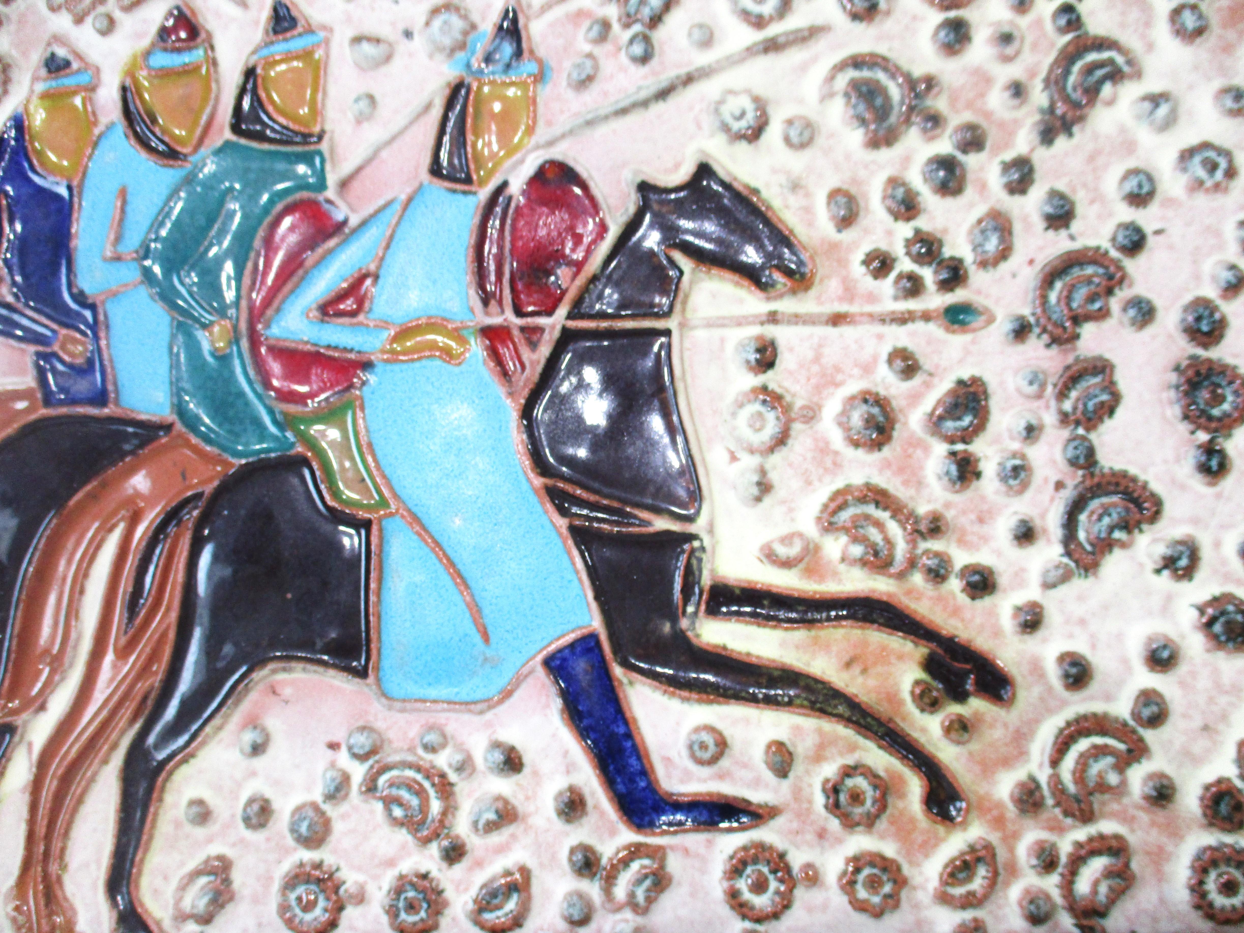 A larger sized pottery art tile with colorful horse back riders on a dimpled glazed back round . Attributed to the iconic Mid Century artist Harris Strong who's many pieces hung in many homes and buildings from the period . Framed in wood and