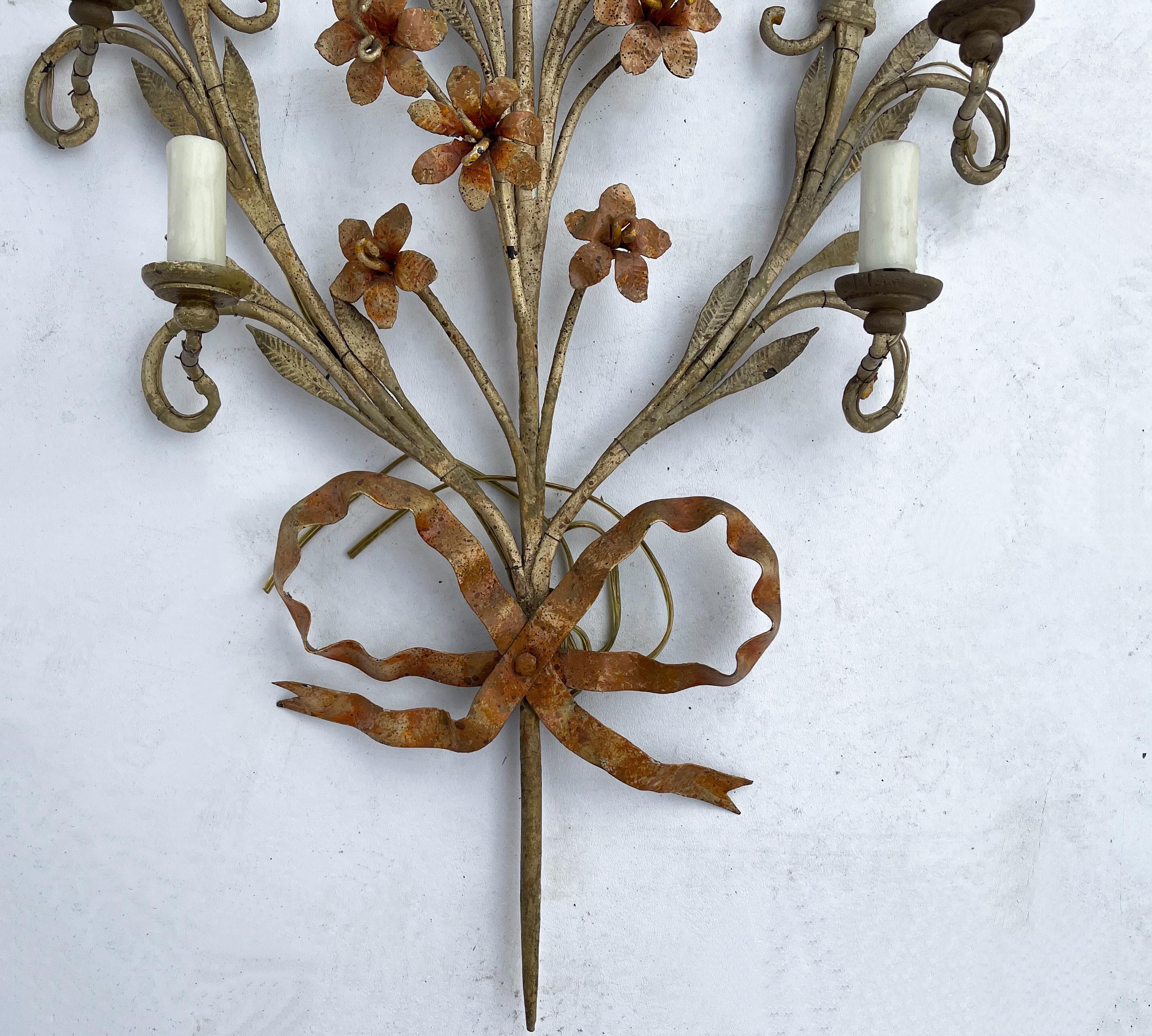 This is a pair of large scale Italian tole floral sconces. They are metal and have a petal form with graduated candle cups. They are in working order.