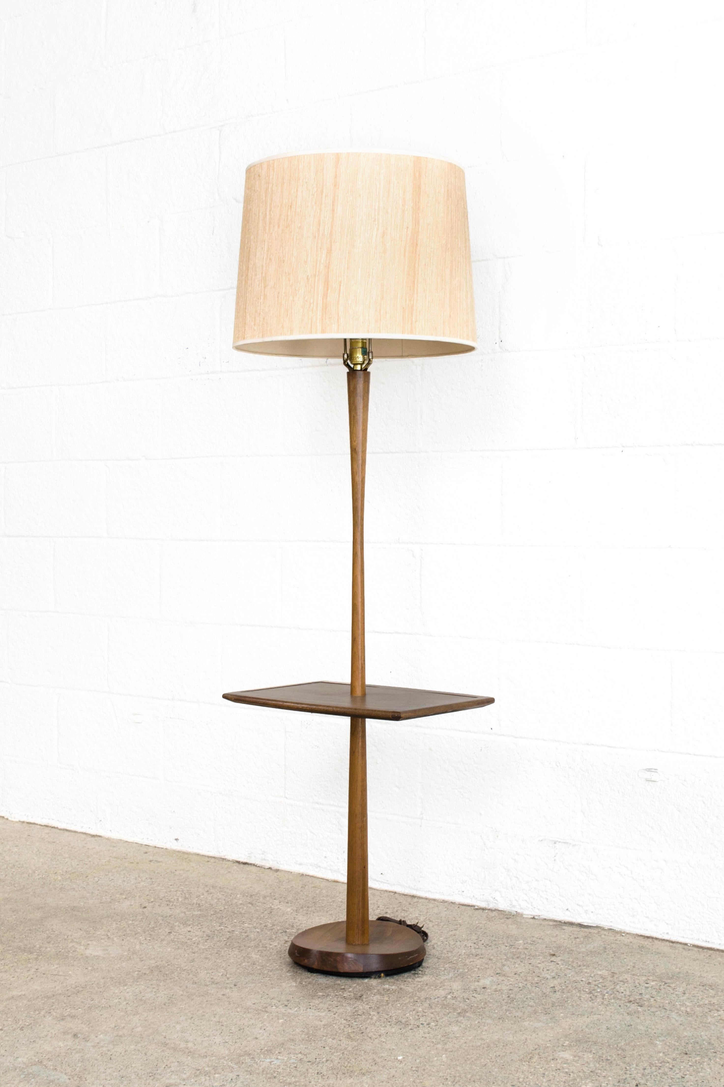 This vintage Mid-Century Modern Laurel Lamp Company sculptural teak floor lamp circa 1960 has a Classic sleek, Minimalist design. The lamp features a beautiful long tapered stem with rectangular table and iconic sculpted concave base. The light has
