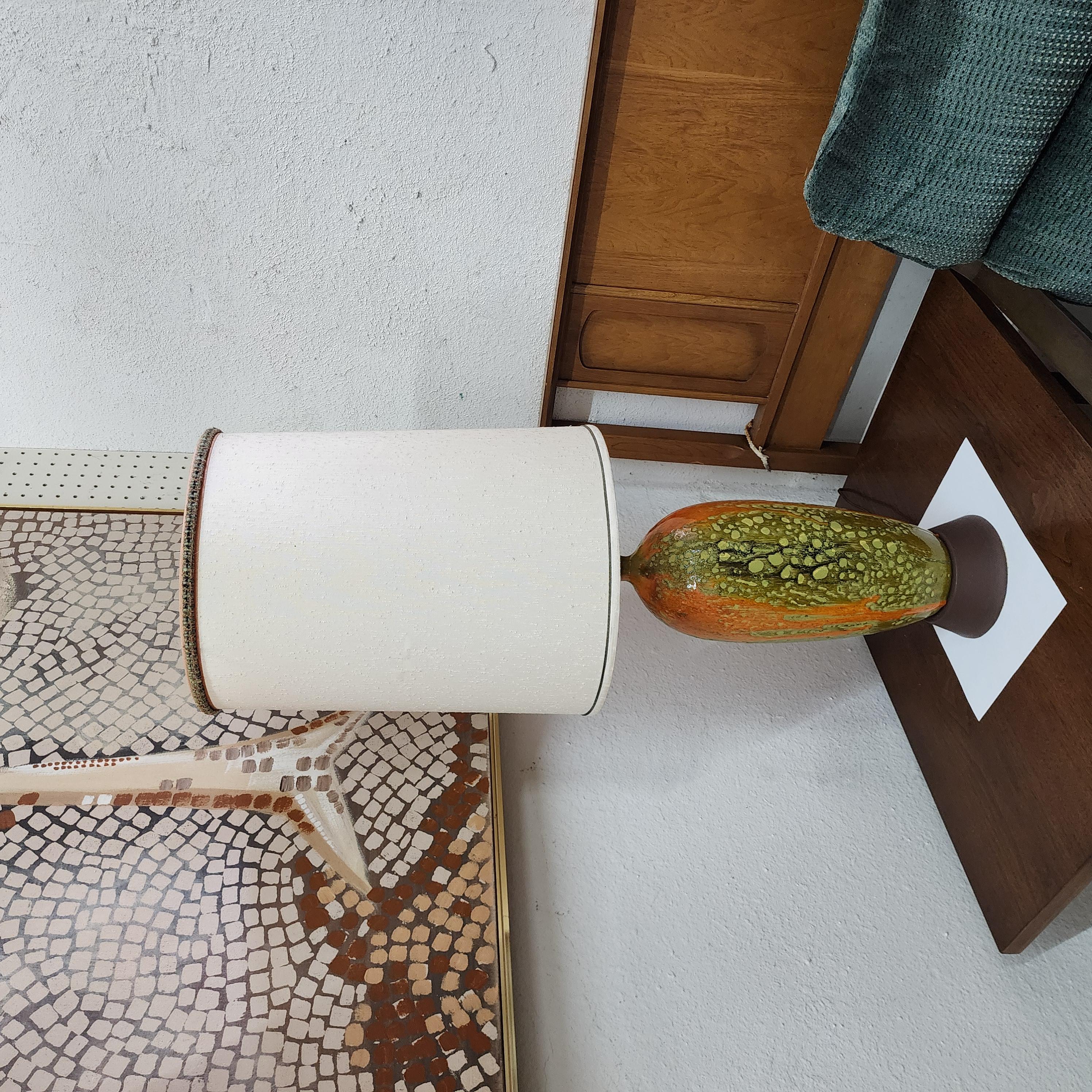 This is a unique mid-century lava glazed ceramic lamp. It has beautiful texture and has brilliant shades for avocado green and orange. It has a green felt bottom to protect the surface it is on. This would be eye catching and stunning in any home,