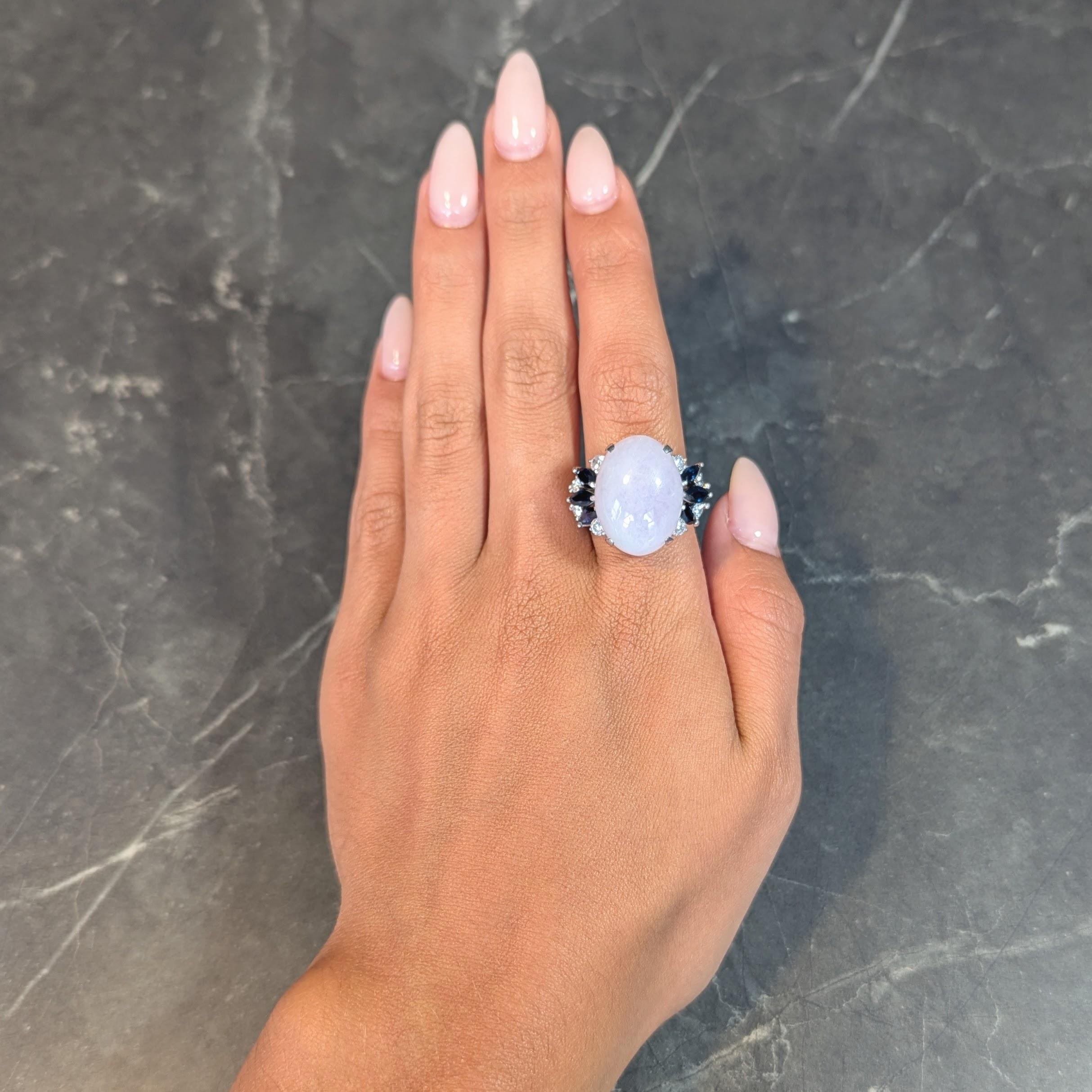 Centering an oval-shaped jade cabochon measuring 21.5 x 16.0 mm 
Translucent, very light purple with white and subtle green mottling 
Prong set in geometric motif basket and flanked by marquise cut sapphires
Weighing approximately 1.70 carats total