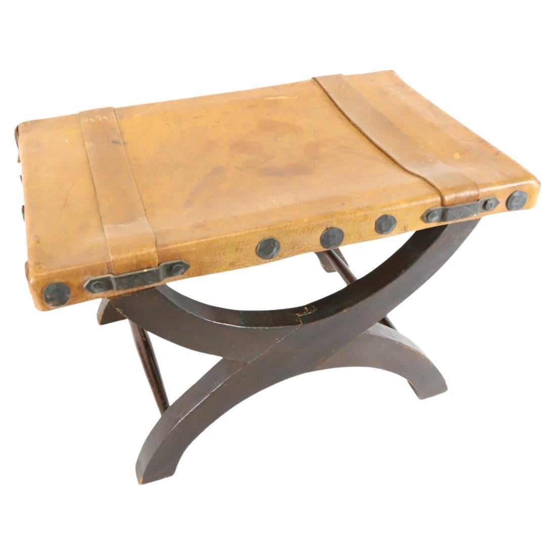 Sgabello revival spagnolo di metà secolo in pelle e legno realizzato in Messico. Pelle marrone chiaro con struttura in legno marrone scuro. Ha accenti in metallo. Realizzato in Messico nel 1960 circa. Etichettato ARTES DE MÉXICO INTERNACIONALES,