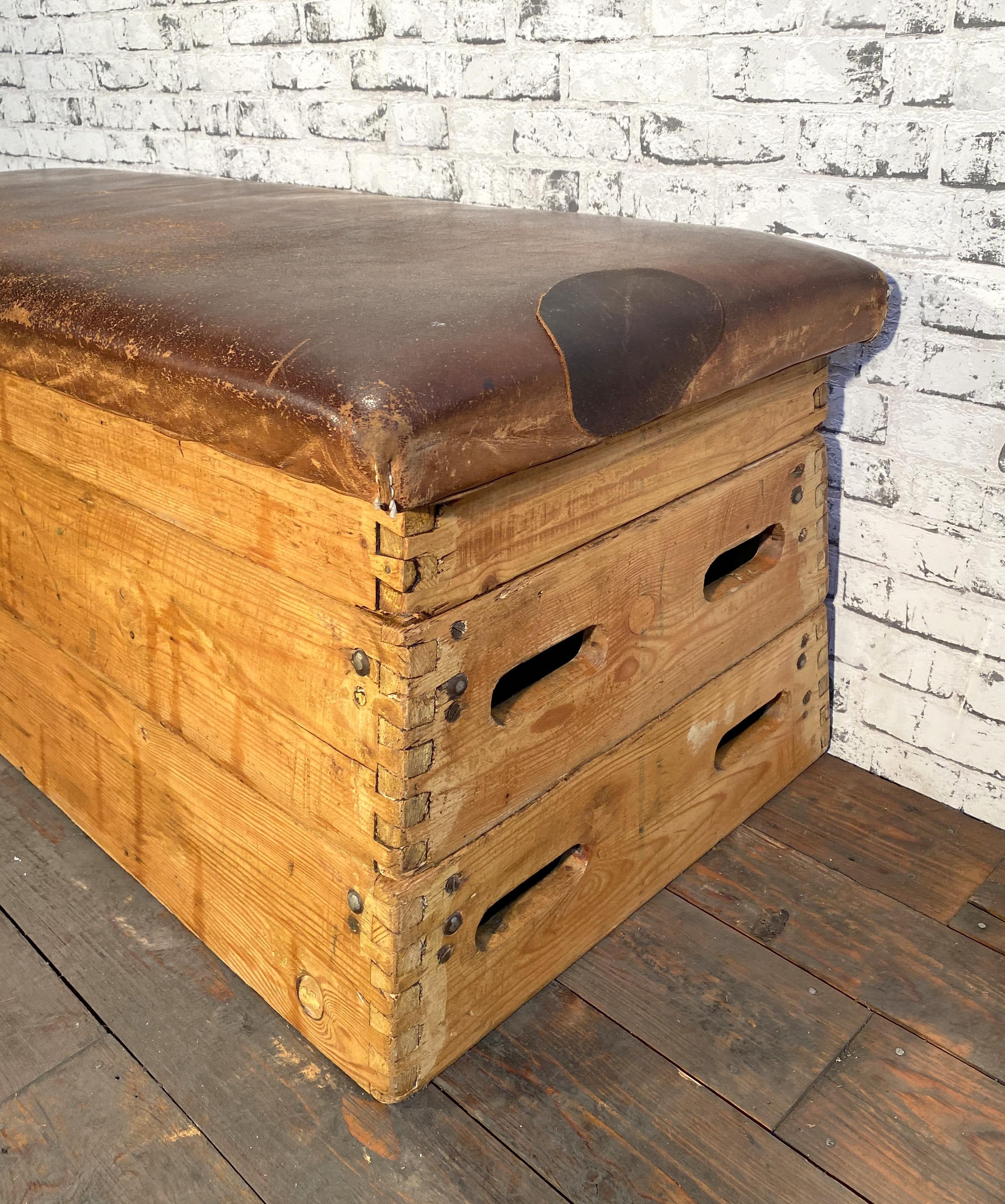 This is a leather gym bench from the 1950s. It features a wooden body and the top from thick leather.