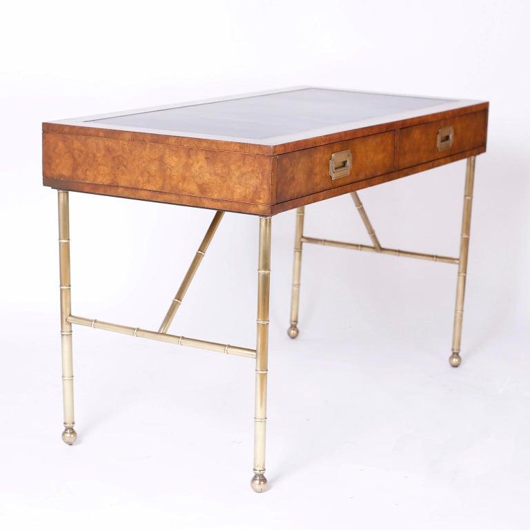 Chic two-drawer writing desk with a tooled black leather top on a burled walnut case over faux bamboo brass legs. Signed Mastercraft Furniture Co. in a drawer.