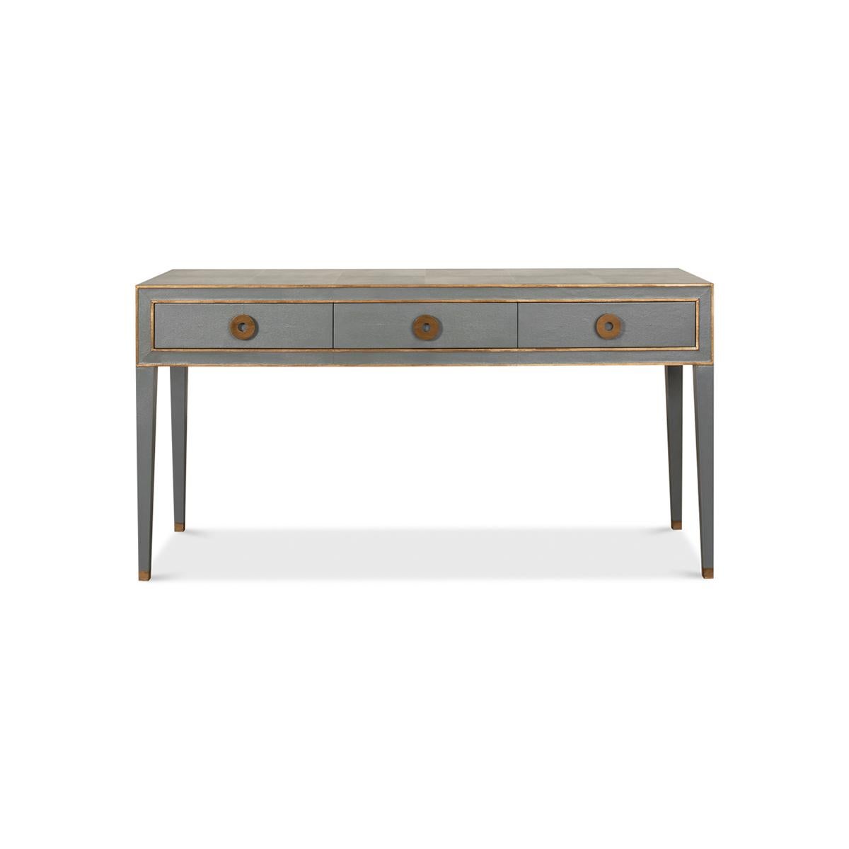 Mid-Century leather wrapped console, a grey embossed faux shagreen wrapped console with three drawers framed in gilt and raised on square tapered legs.

Dimensions: 64