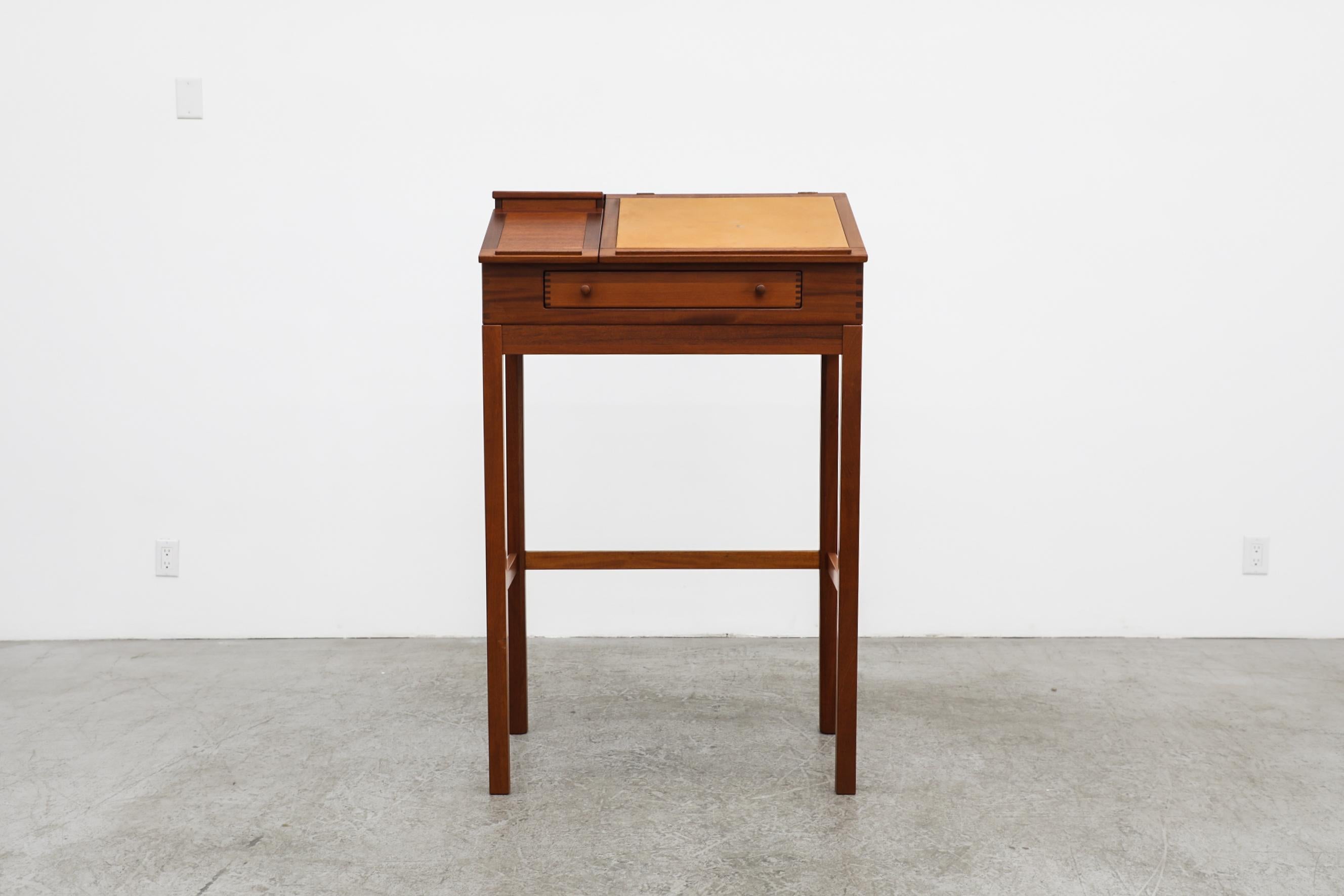The top with writing pad and built in notebook holder, with storage inside and a drawer underneath. In original condition with visible wear, consistent with its age and use.

Mid-Century designed lectern by Andreas Hansen, Denmark, 1960's. The