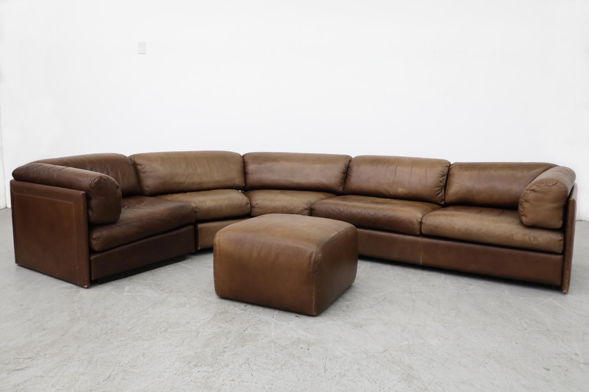 Midcentury Leolux thick natural brown leather curved sectional sofa with matching ottoman. In original condition with visible wear and fading to the leather. This set has 3 single pieces; a single seat end/corner, an angled 2 seater, and a straight