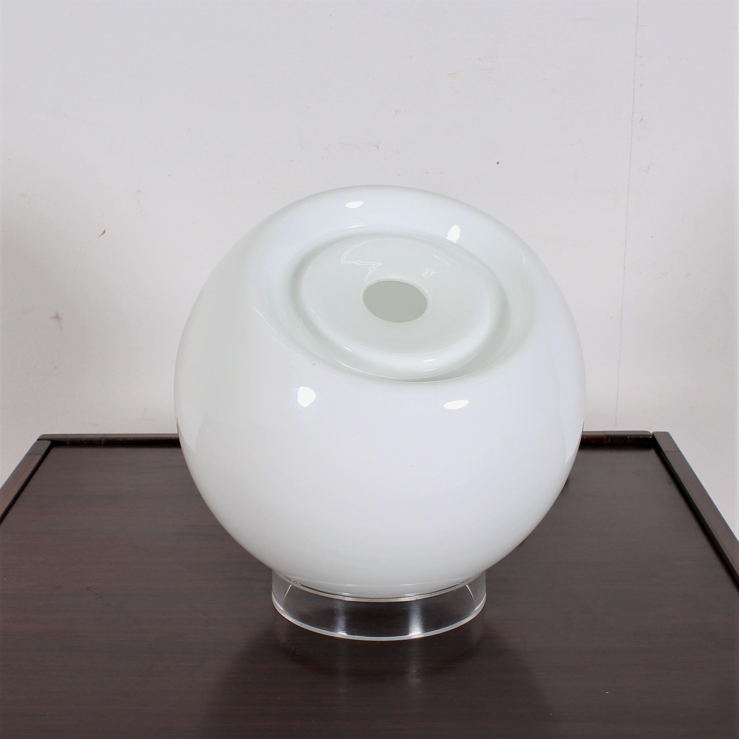 Elegant table lamp composed of a white glass globe that rotates on a perspex ring directing the light wherever you want. The blown glass has maintained its shiny effect. It is perfect for projecting light in a corner, in a bookcase, on a piece of