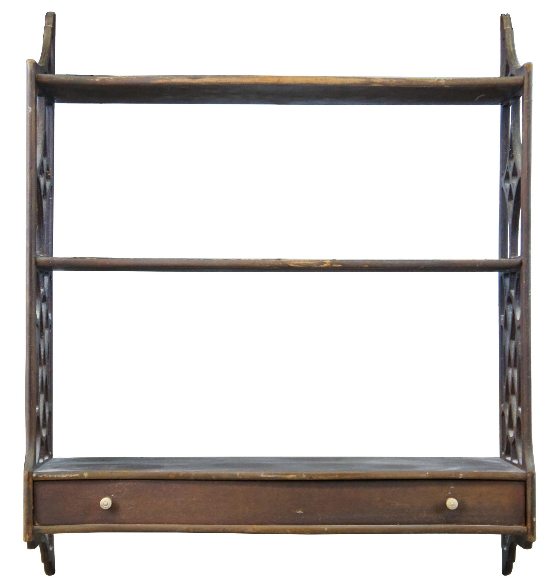 Mid 20th century Chippendale style Lewis Butler wall shelf, #131. A serpentine form made from mahogany with fretwork siding and lower drawer. 

Measures: 29.25