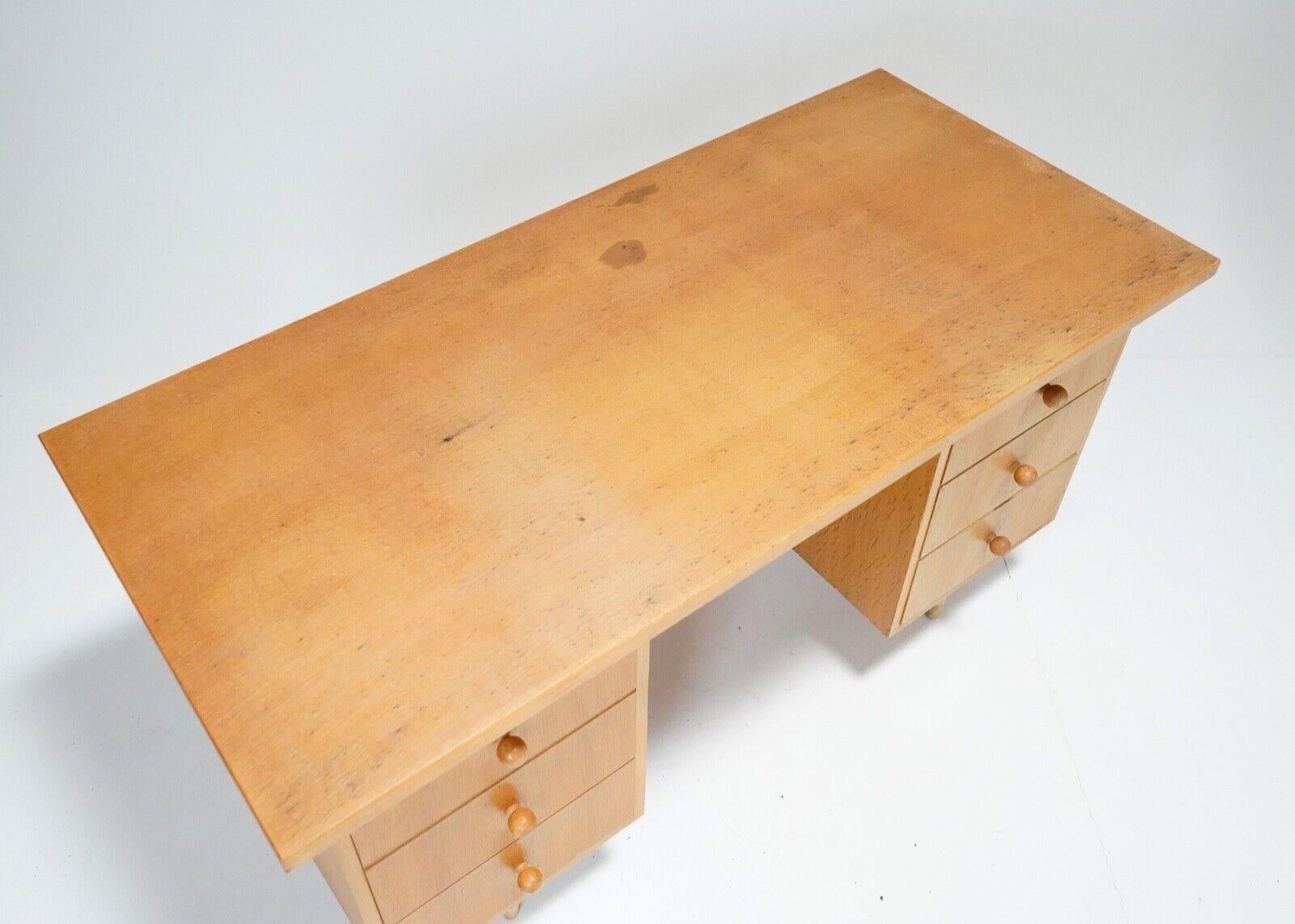 A Mid Century Light Oak veneer desk by British furniture maker Meredew.
This simple desk has six drawers with lovely little spherical pulls. 
Ample storage and a good size surface to work on. 
A few stains on the top and a few chips to the veneer,