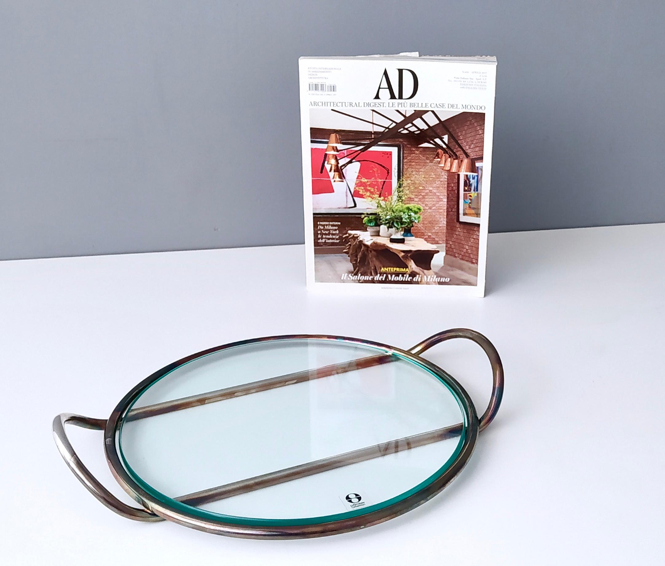 1960s.
This is a great silver plated glass serving dish, which can also be used as a trivet.
Its simple design was created by Lino Sabattini in Italy, circa 1960s. 
This is a vintage piece, therefore it might show slight traces of use, but