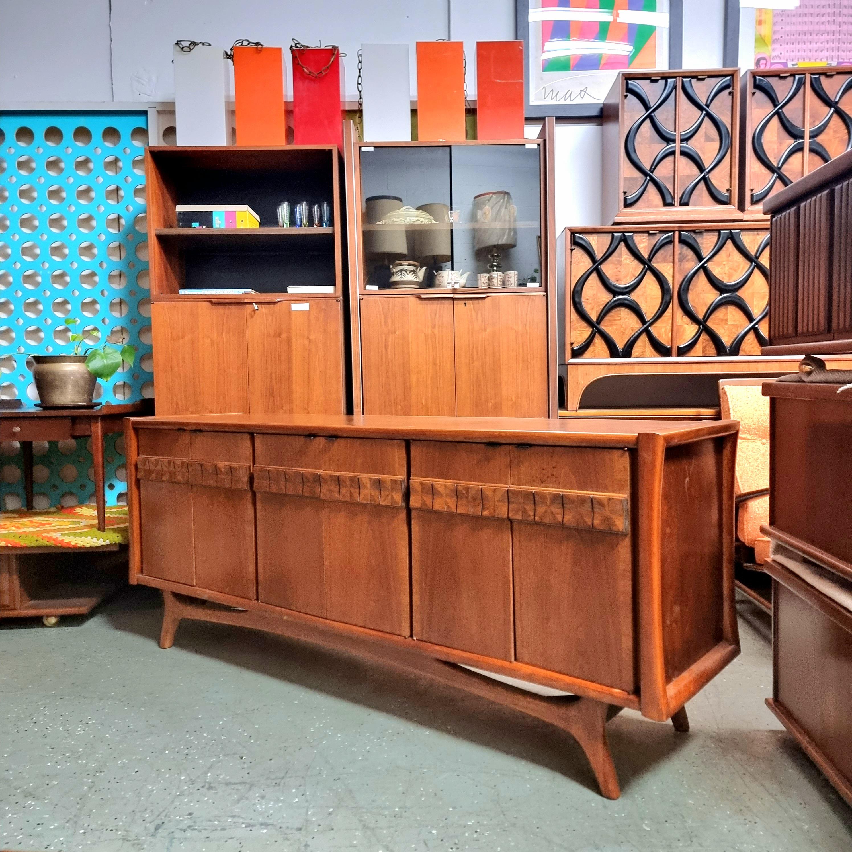 
Here is a large Mid Century credenza. Beautifully crafted, shows off a slight curve on the sides for an atomic look, beautiful geometric carved wood detail on doors and an amazing leg and stretcher detail at base for a killer silhouette!. Has