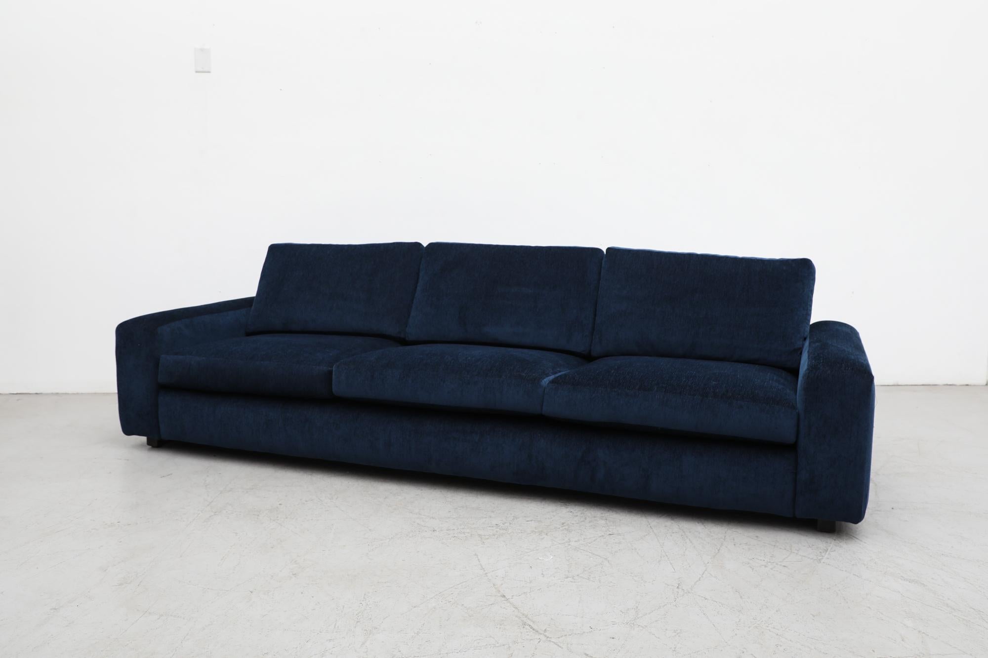 Jan Des Bouvrie designed, newly upholstered XL sapphire blue chenille sofa with deep, low seating perfect for lounging. Some visible markings to wood feet consistent with its age and use but otherwise impressive condition. Big and comfy!