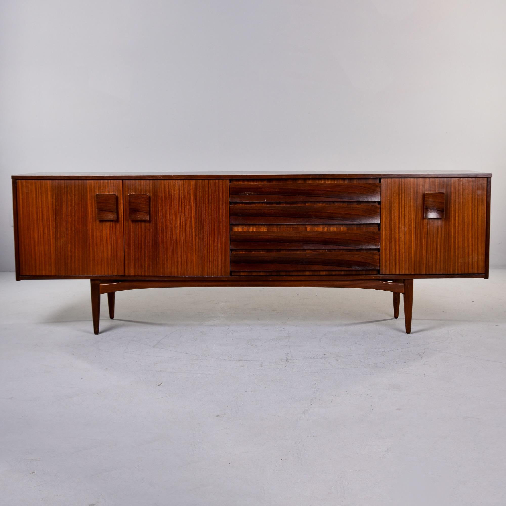 Found in England, this mahogany and rosewood buffet or credenza is by Grange of London and dates from the 1960s. The base features curved stretchers and four slender, tapered legs. The cabinet portion is mahogany with contrasting rosewood drawer