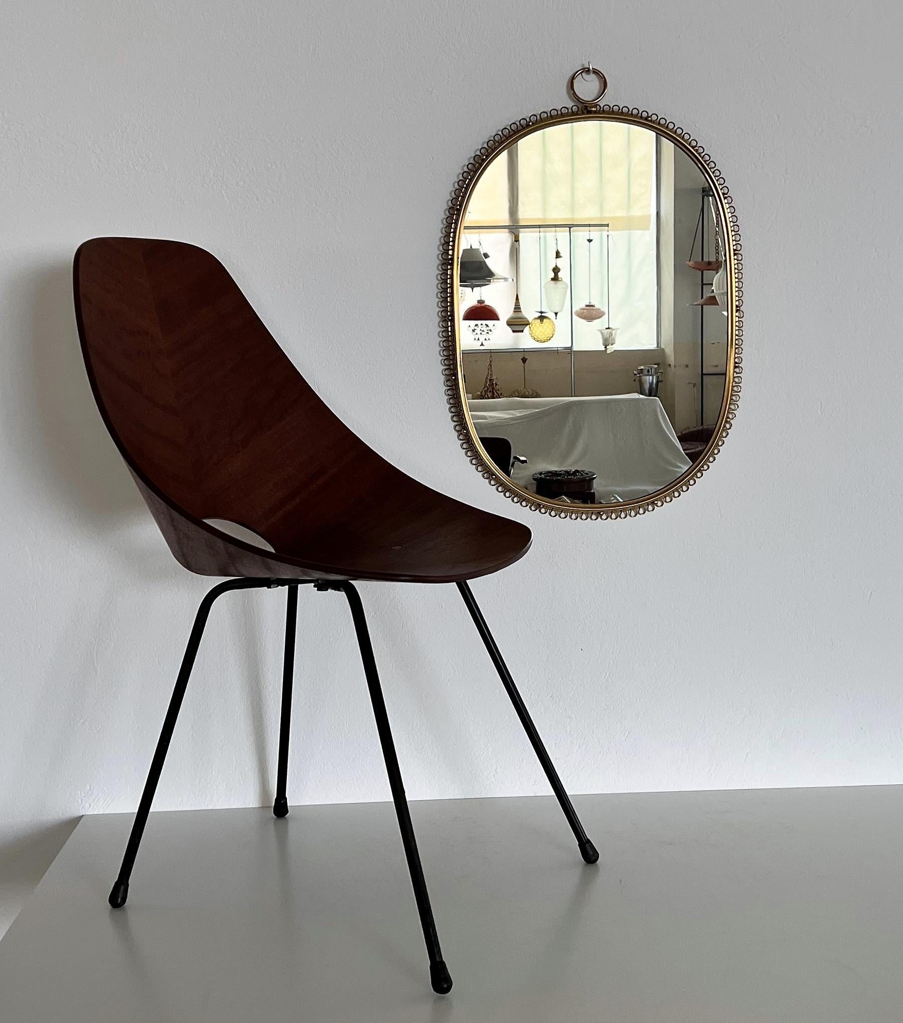 Gorgeous wall mirror designed by Austrian Josef Frank and manufactured in Sweden by Svenskt Tenn in the midcentury.
This mirror is made of full shiny brass frame with spiral loop frame around and big round hanging hook on top. 
You can easily