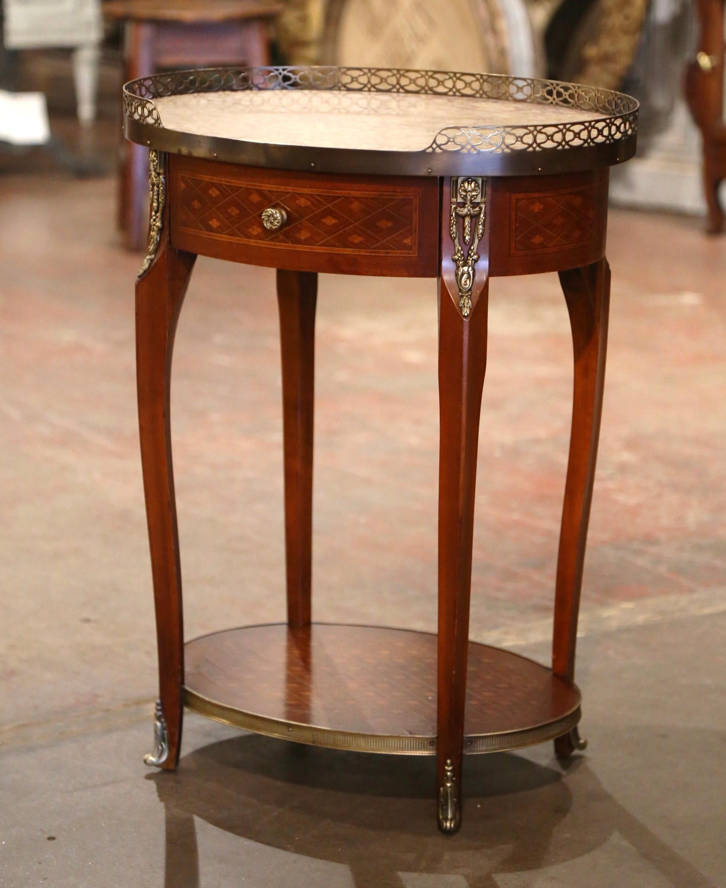 Crafted in France circa 1950 and built of walnut, the oval table sits on four cabriole legs decorated with brass mounts at the shoulders, ending with bronze sabots. The side table features detailed marquetry work around the apron, and is further