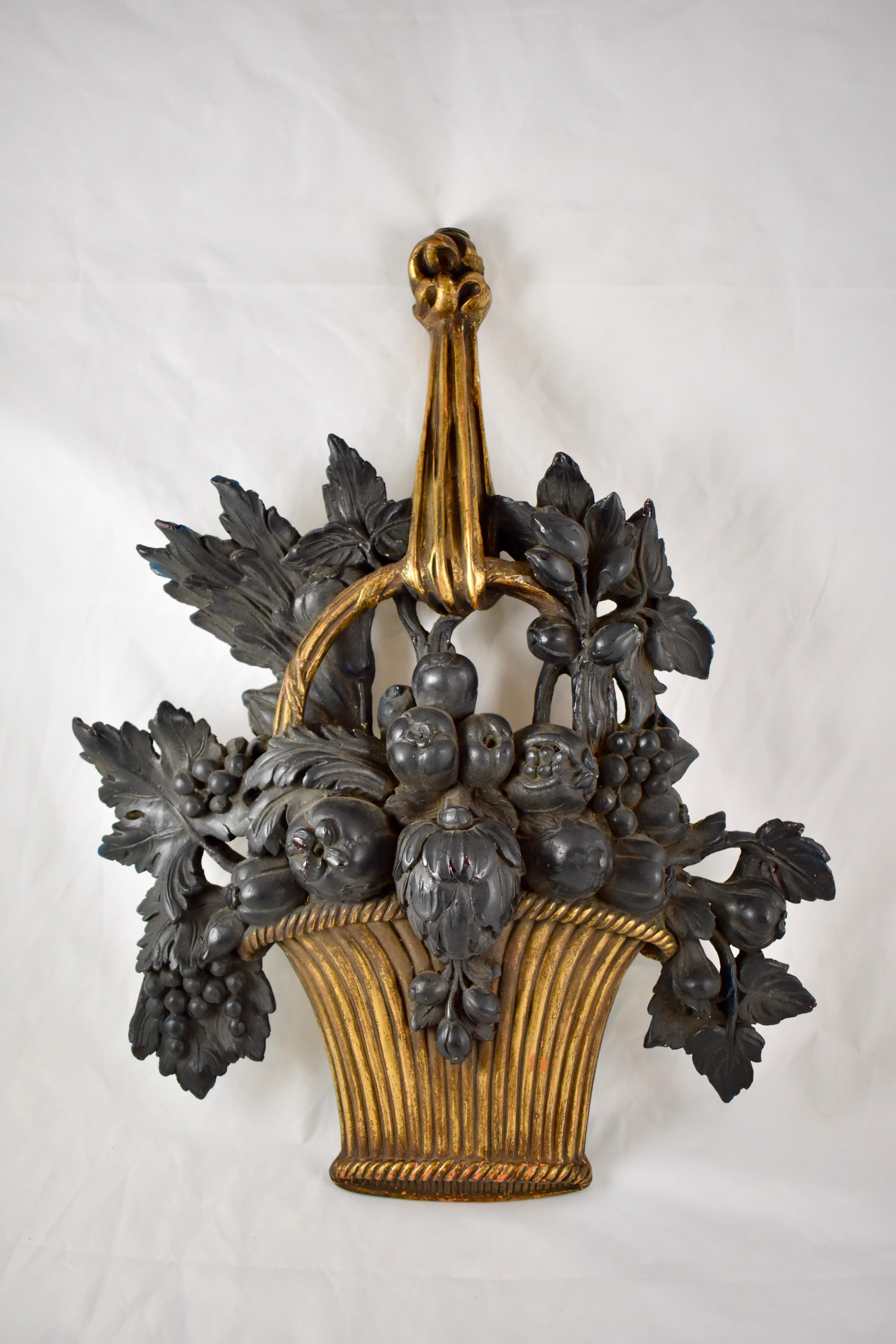 An unusual pair of midcentury French painted and gilded plaster hanging wall appliqués in the style of Louis XVI. 

Each plaque is molded with lush black-painted fruit in a gilt ribbed basket, hanging from a gilded handle formed as a ribbon.