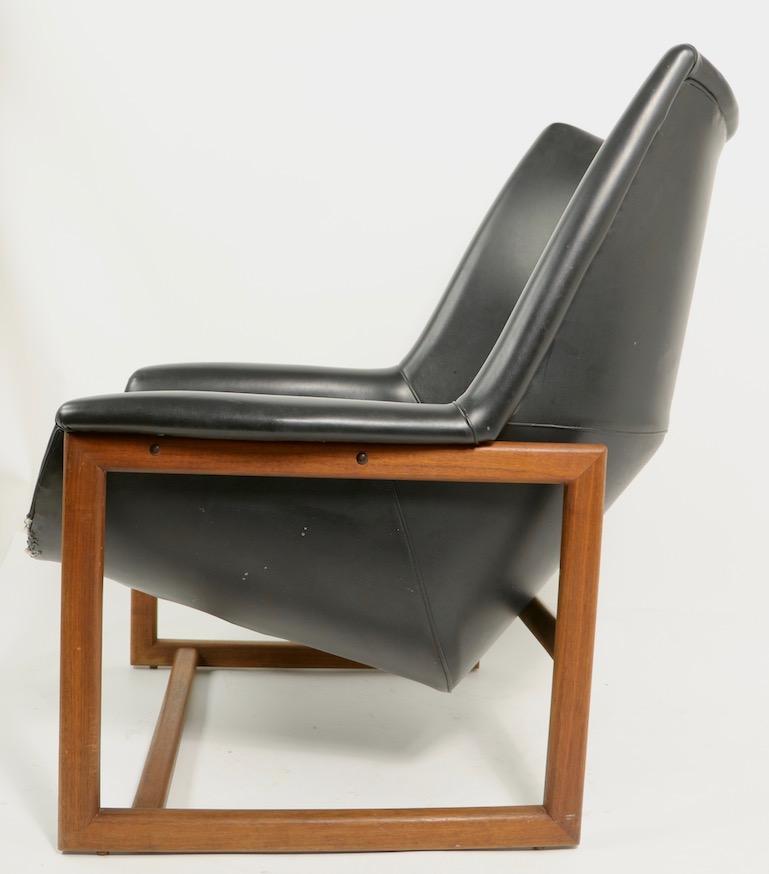 Chic and sophisticated architectural lounge chair, after the iconic Risom big chair. The chair has a large upholstered seat which is set in a solid walnut frame. The chair will need to be reupholstered, but is in great structural condition, solid