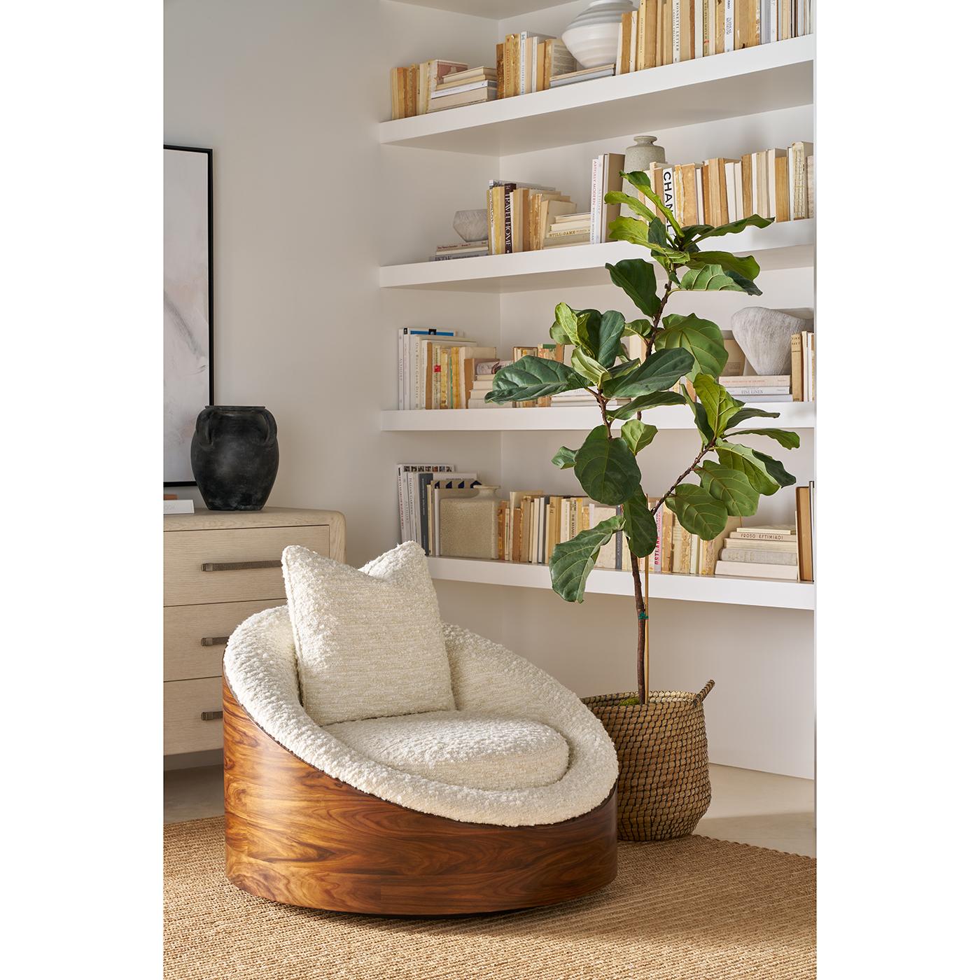 Upholstered in soft Boucle fabric, its curved form nestles into a beautifully grained walnut base, creating a striking contrast of texture and tone. The lounge chair’s gently sloped design supports relaxed lounging, while its swivel base adds ease