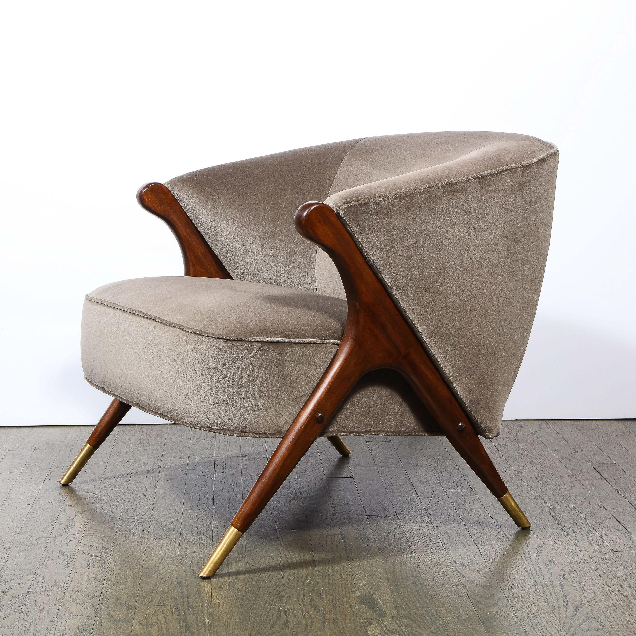 This stunning and understated lounge chair realized by the esteemed Karpen of California, circa 1960. It features splayed legs in walnut resting on conical brass sabots. The legs adjoin at a curvilinear wishbone joint, continuing their angled ascent