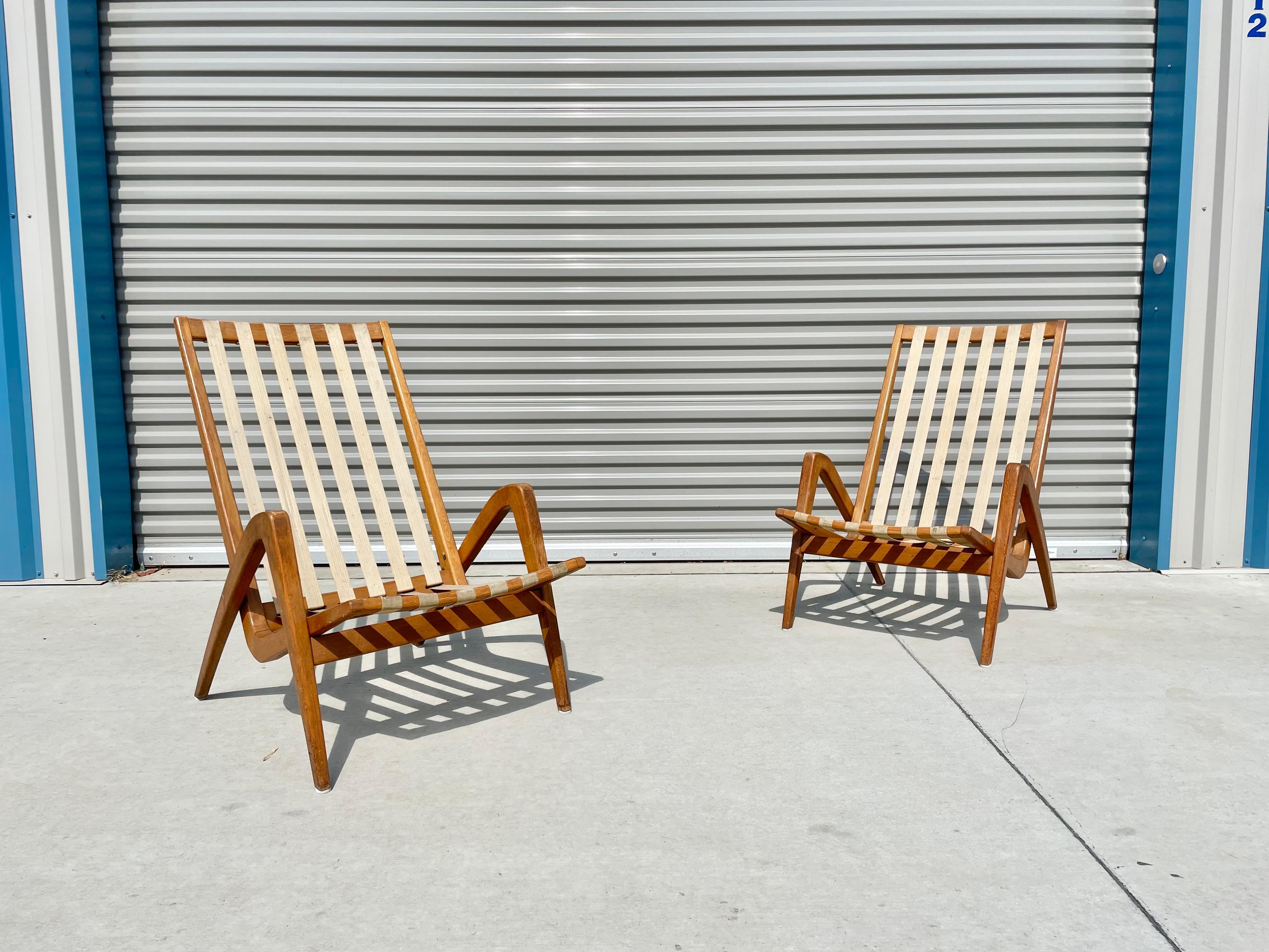Midcentury floating lounge chairs were designed by Jan Vanek for Uluv Czechosloavkia in Slovenia circa 1960s. These chairs stand out for their floating design because the walnut frames give the illusion that the chairs are floating. These chairs