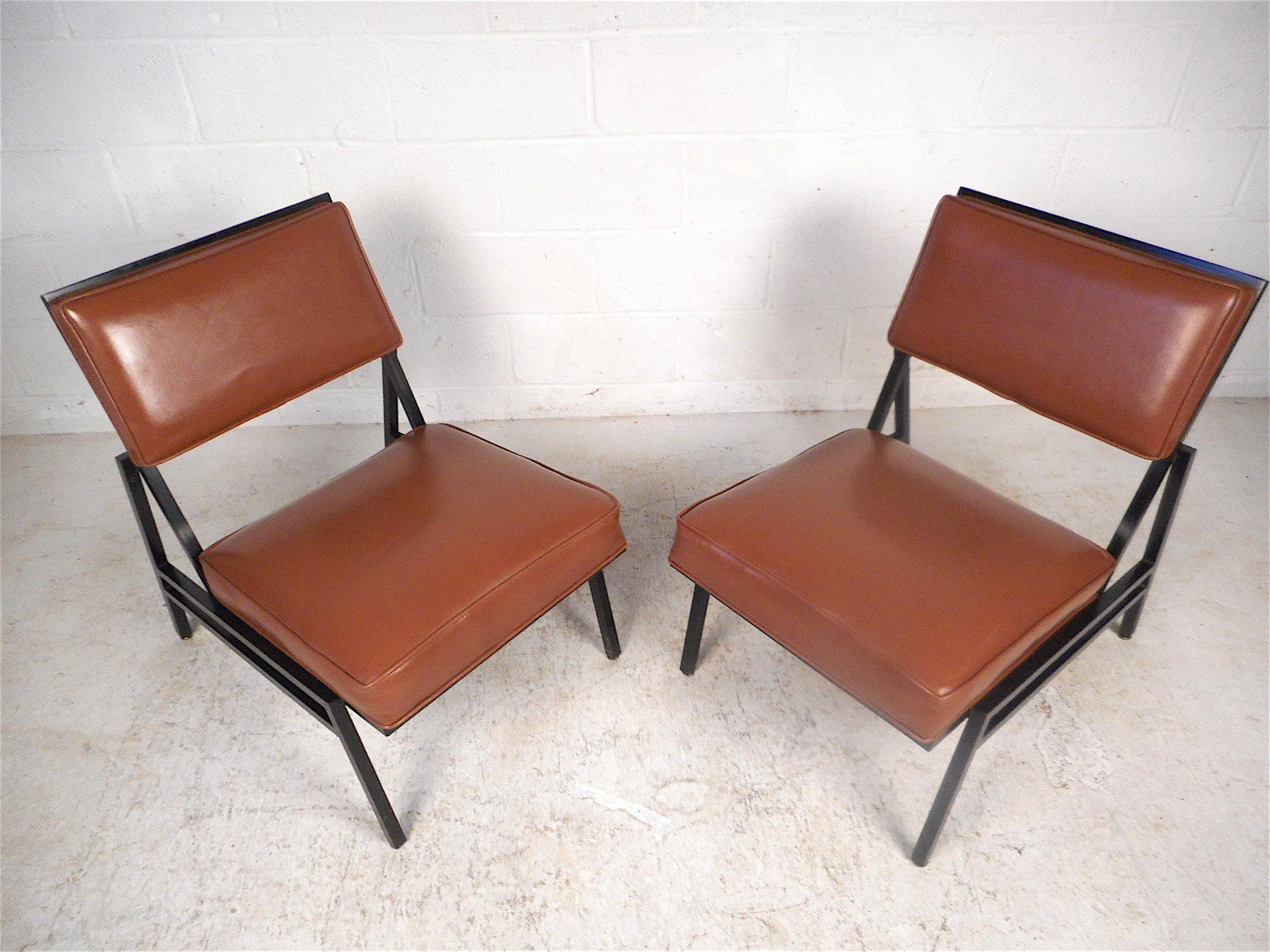 Stylish Mid-Century Modern lounge chairs by Steelcase Inc. Sleek angular design reminiscent of Florence Knoll. Sturdy metal frames support spacious seating areas which are covered in a vintage faux-leather upholstery. This pair is sure to prove a