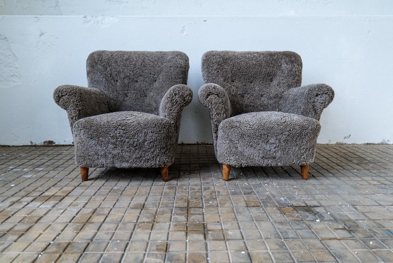 Pair of Swedish modern lounge chairs, with the typical curvy look of its time.
These ones are fully restored and reupholstered with black/grey sheepskin - Shearling.
Beautiful to look at and cozy to sit in. The legs made in stained birch.