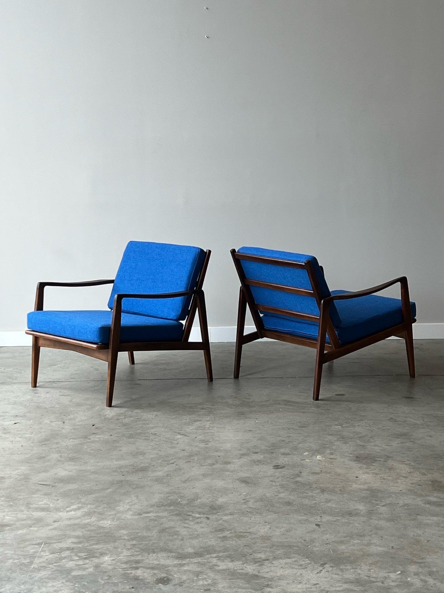 A pair of mid-century lounges. Wooden frames with sculpted arms and accents. Featuring a slat back and tapered legs. This pair looks great from both the front and side profile.

We have newly reupholstered the pair with new foam and in a vibrant